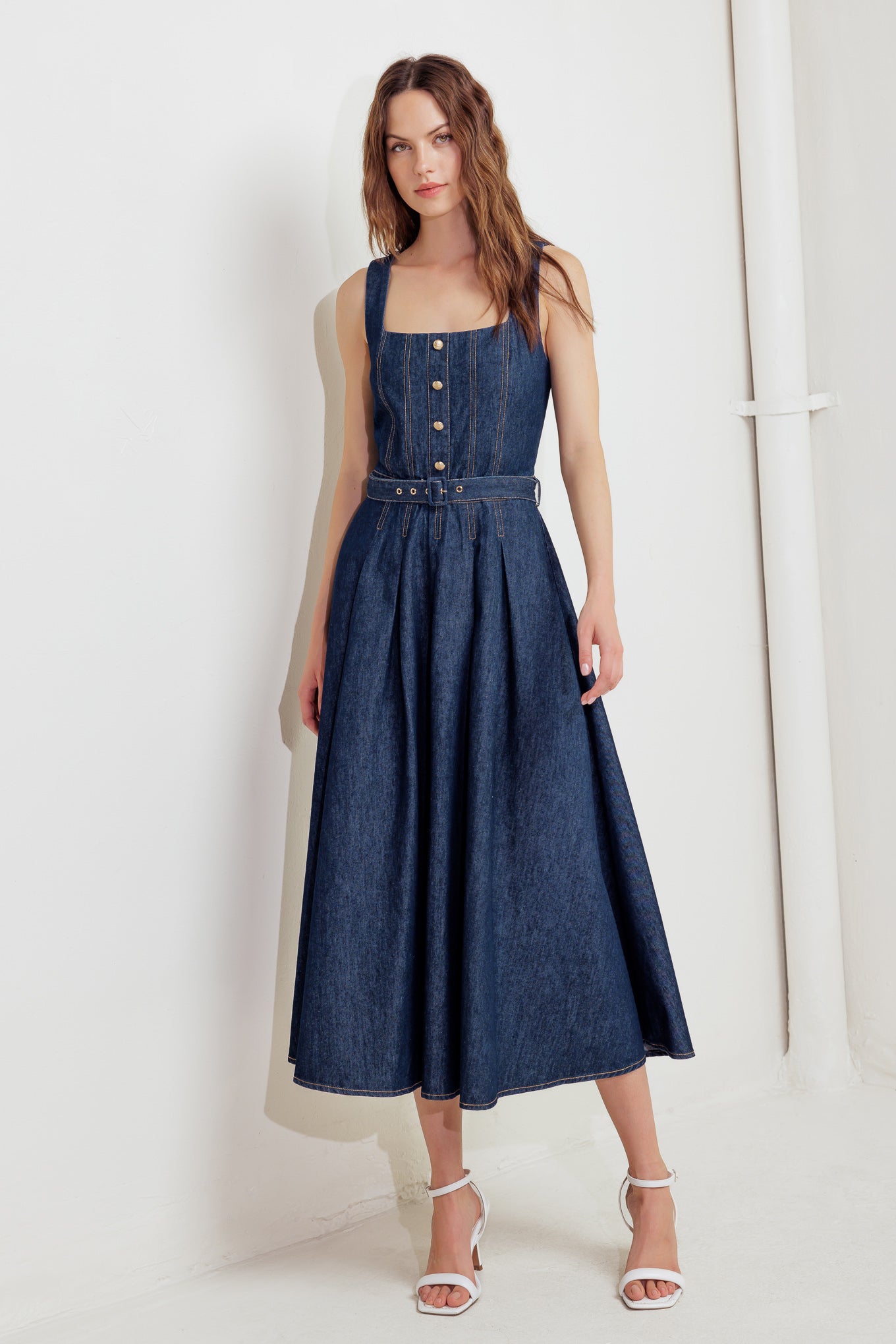 A washed denim midi dress featuring square neckline, sleeveless, self belt and back zipper closure