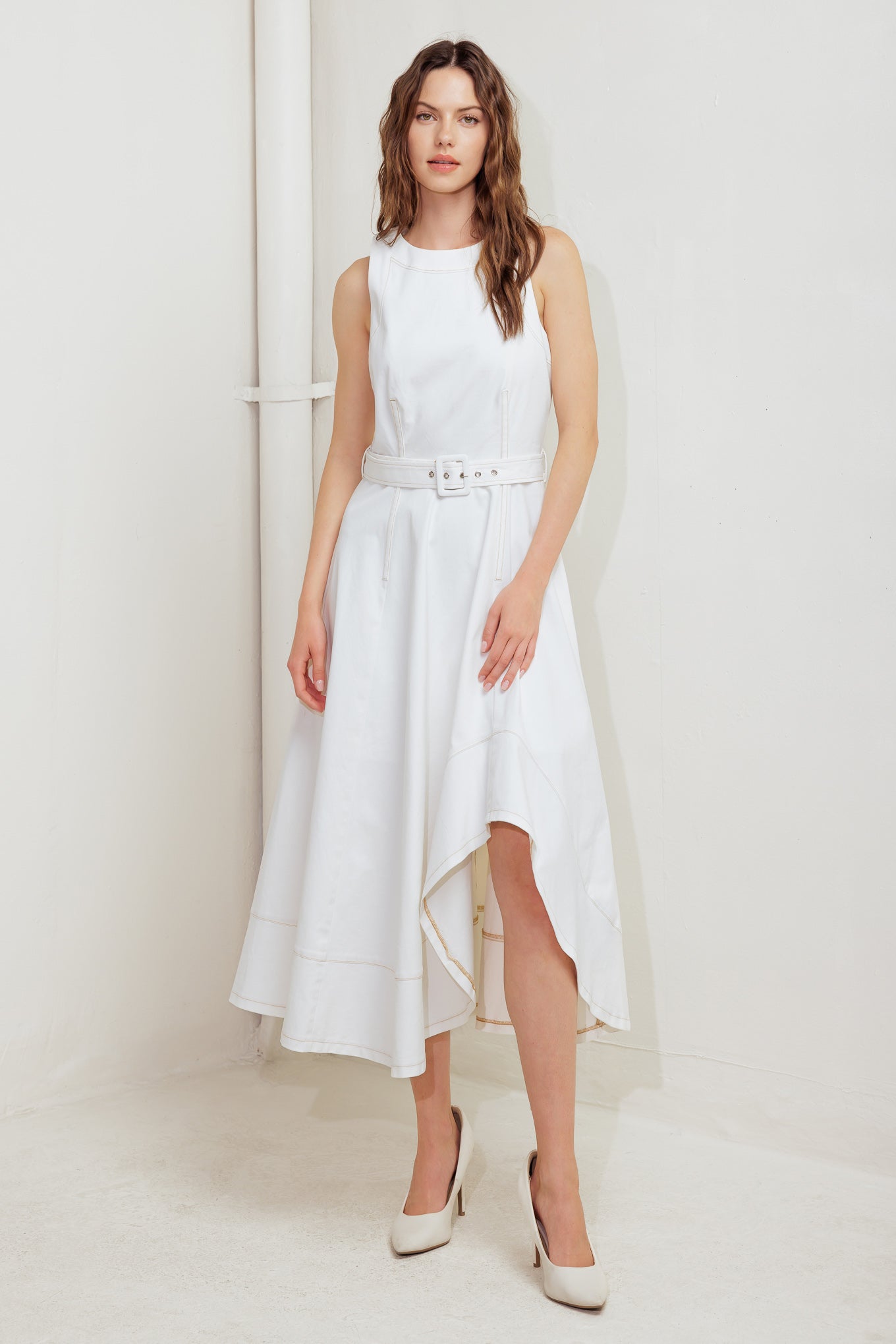 A solid white woven midi dress featuring round neckline, sleeveless, self belt, circle skirt with side hi-lo and back zipper closure