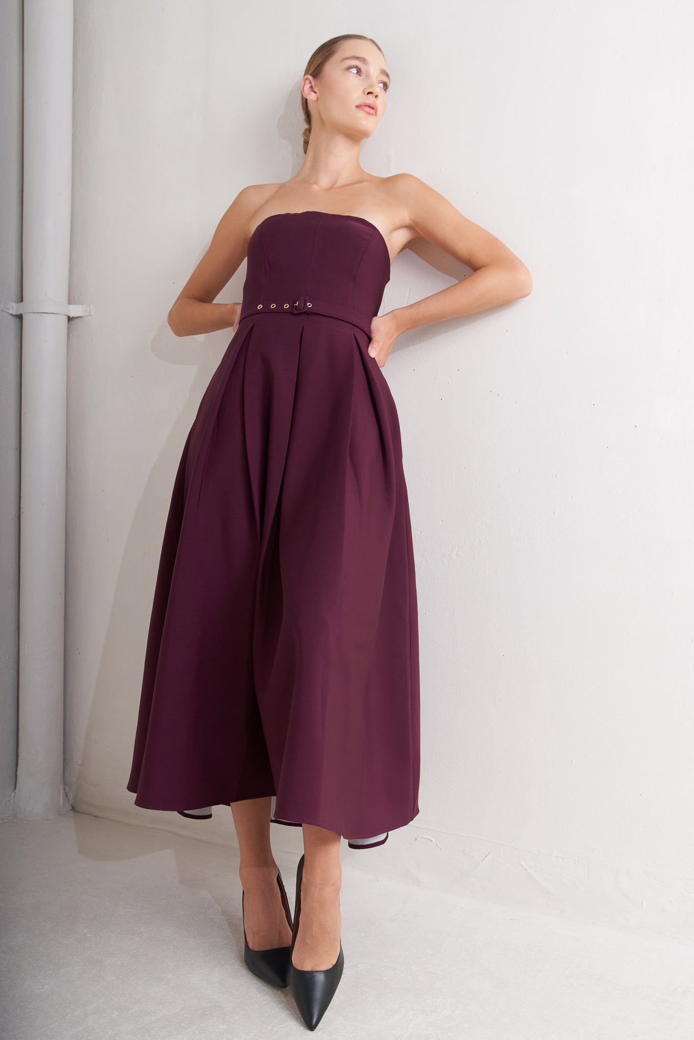 A solid woven mid dress featuring strapless, self belt, full skirt and back zipper closure