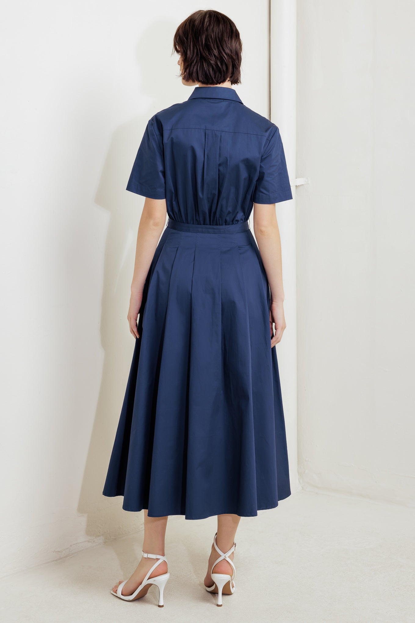 A solid woven midi dress featuring collar, short sleeve, front pocket, button down, self belt and full skirt