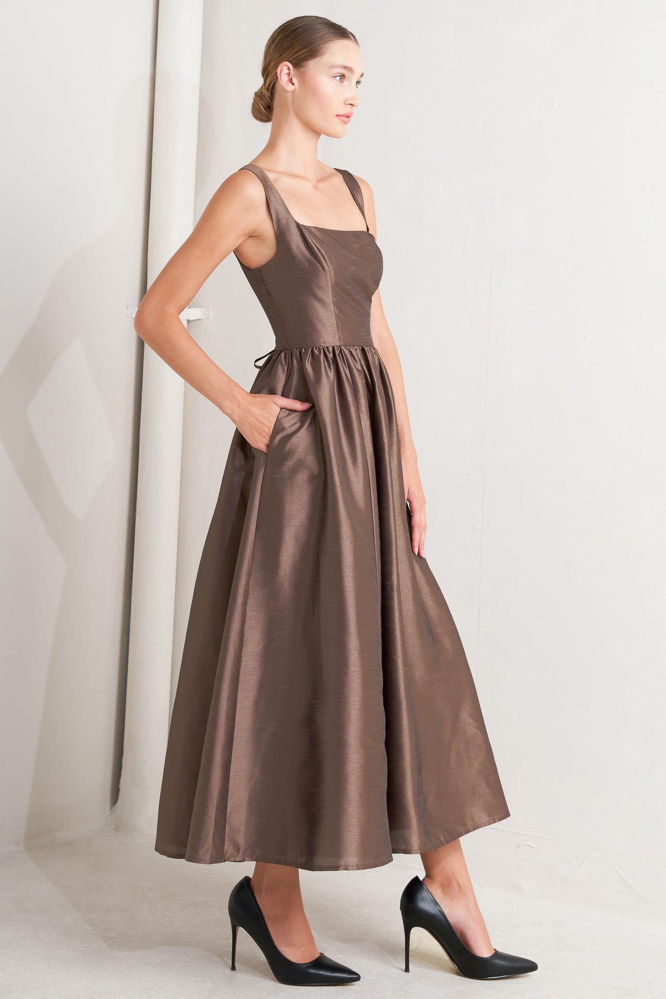 A solid woven midi dress featuring straight neckline, sleeveless, full skirt, back lace up detail and side zipper closure