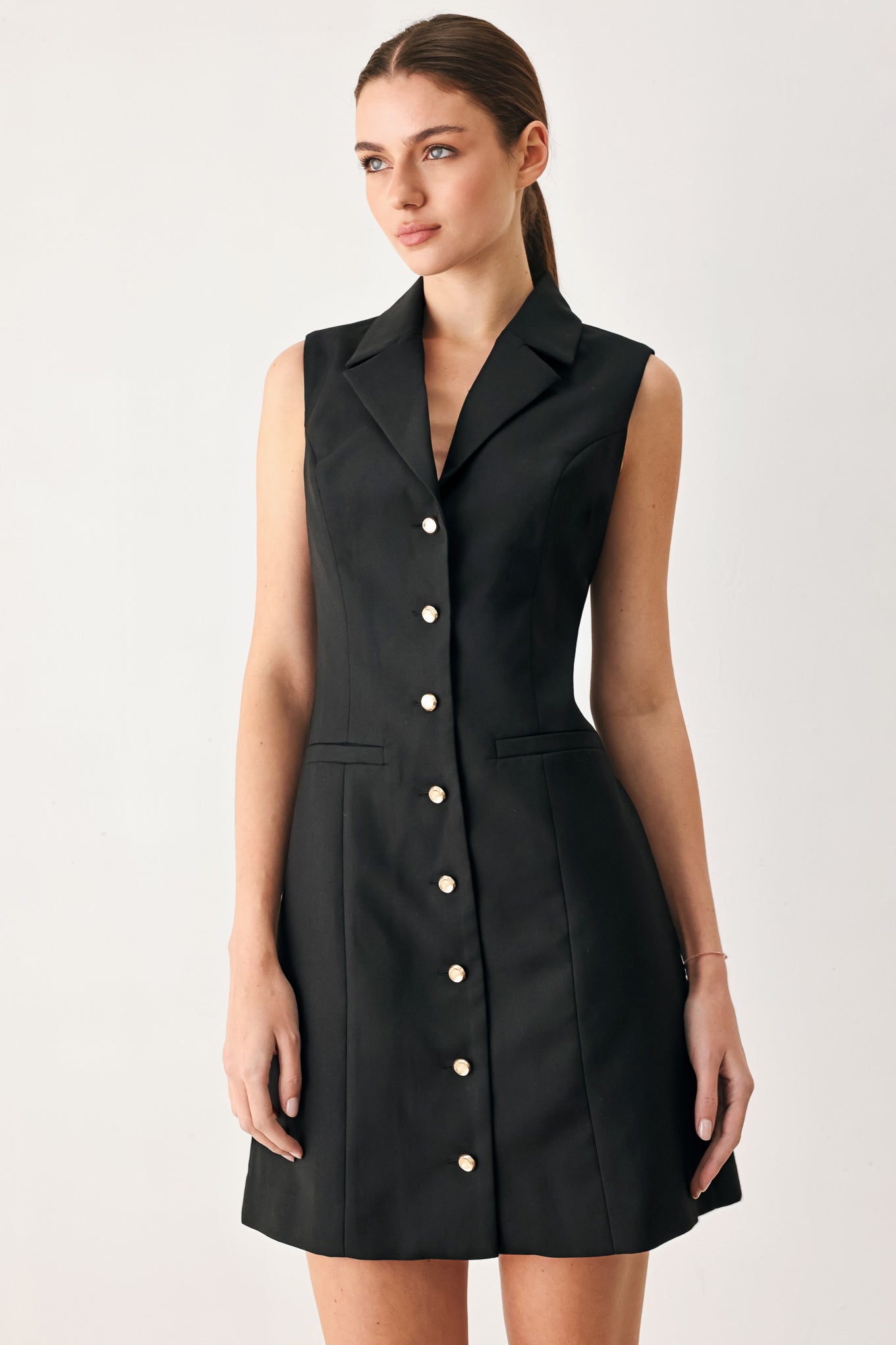 Woman wearing a black sleeveless mini dress featuring blazer collar and front button down | FREEMARKET