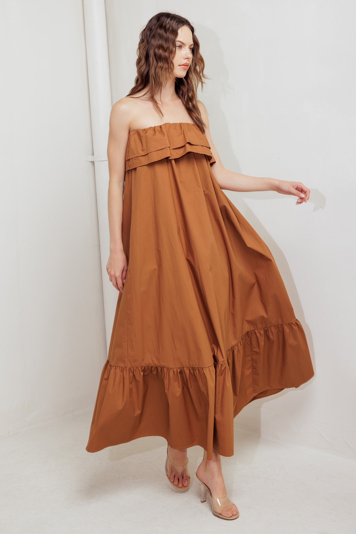 A solid woven midi dress featuring strapless with double flounce, contrasting belt and ruffled hemline