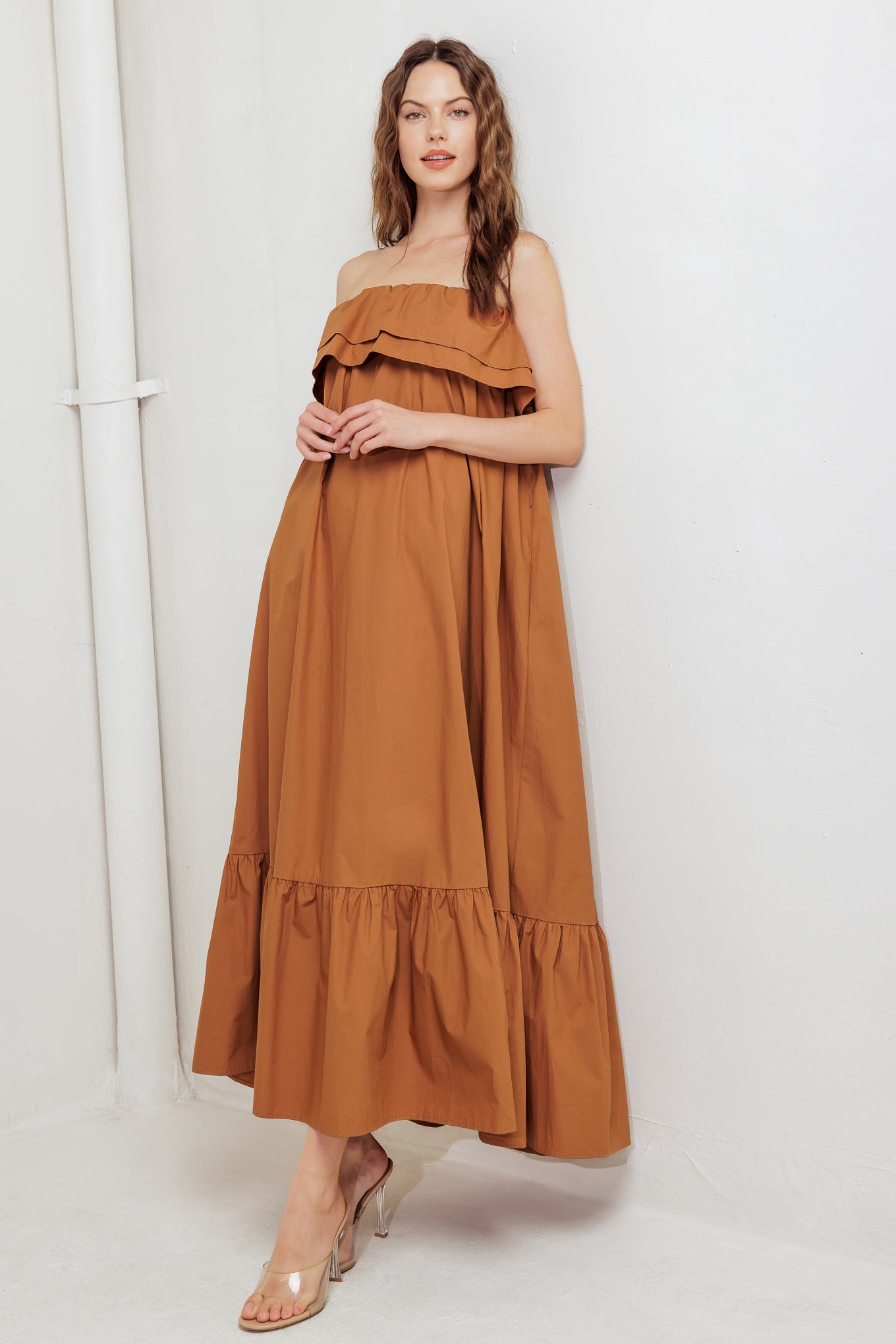 A solid woven midi dress featuring strapless with double flounce, contrasting belt and ruffled hemline