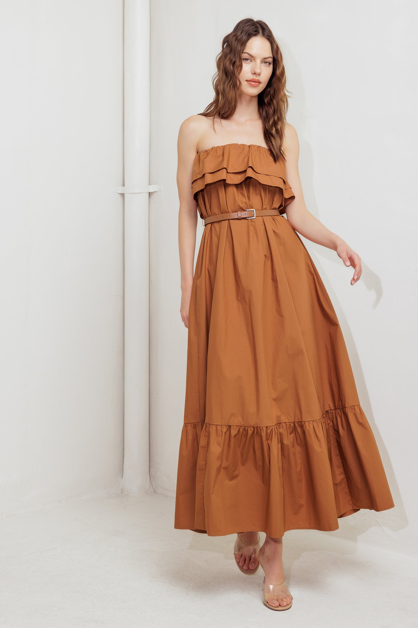 A solid woven midi dress featuring strapless with double flounce, contrasting belt and ruffled hemline