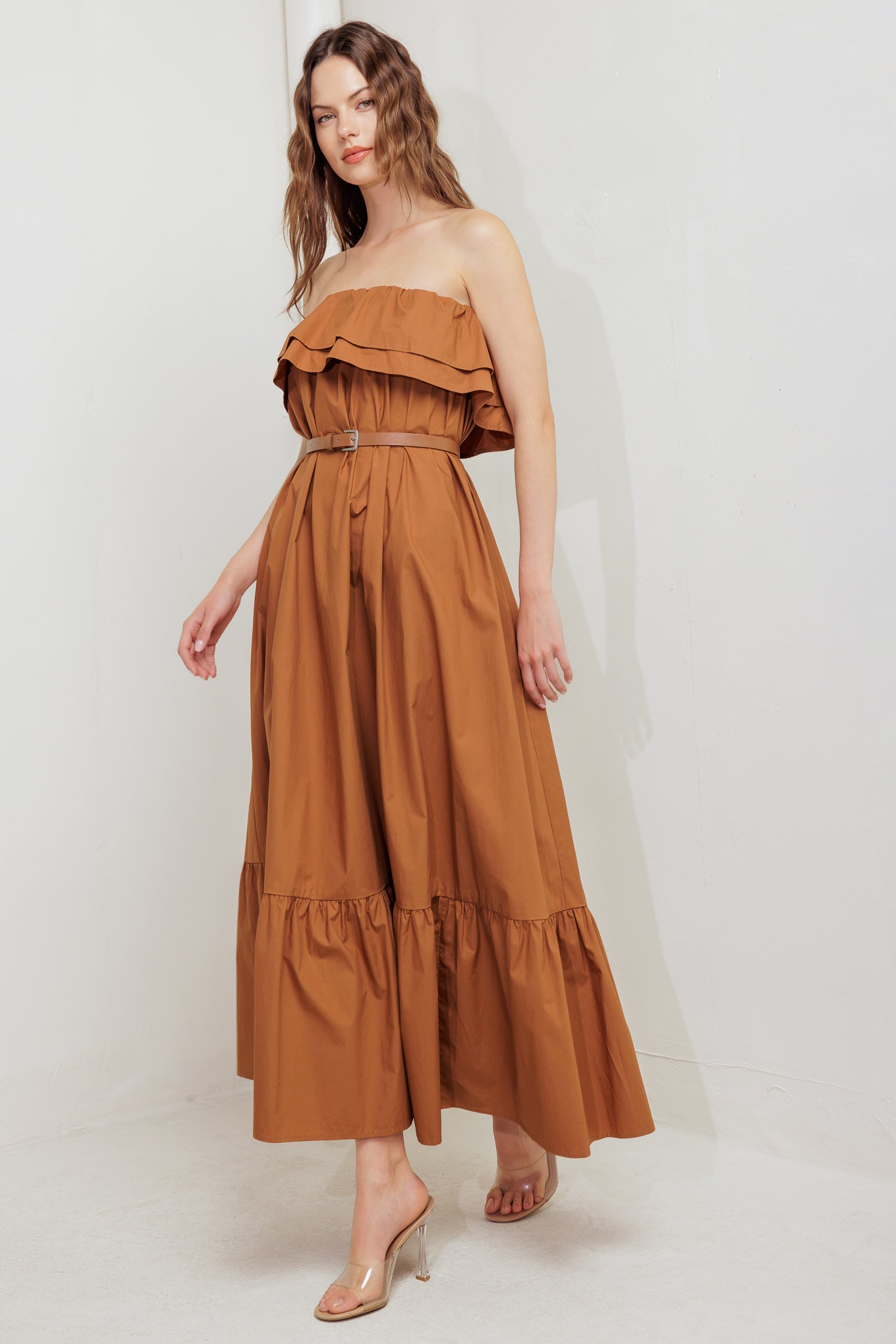 A solid woven midi dress featuring strapless with double flounce, contrasting belt and ruffled hemline