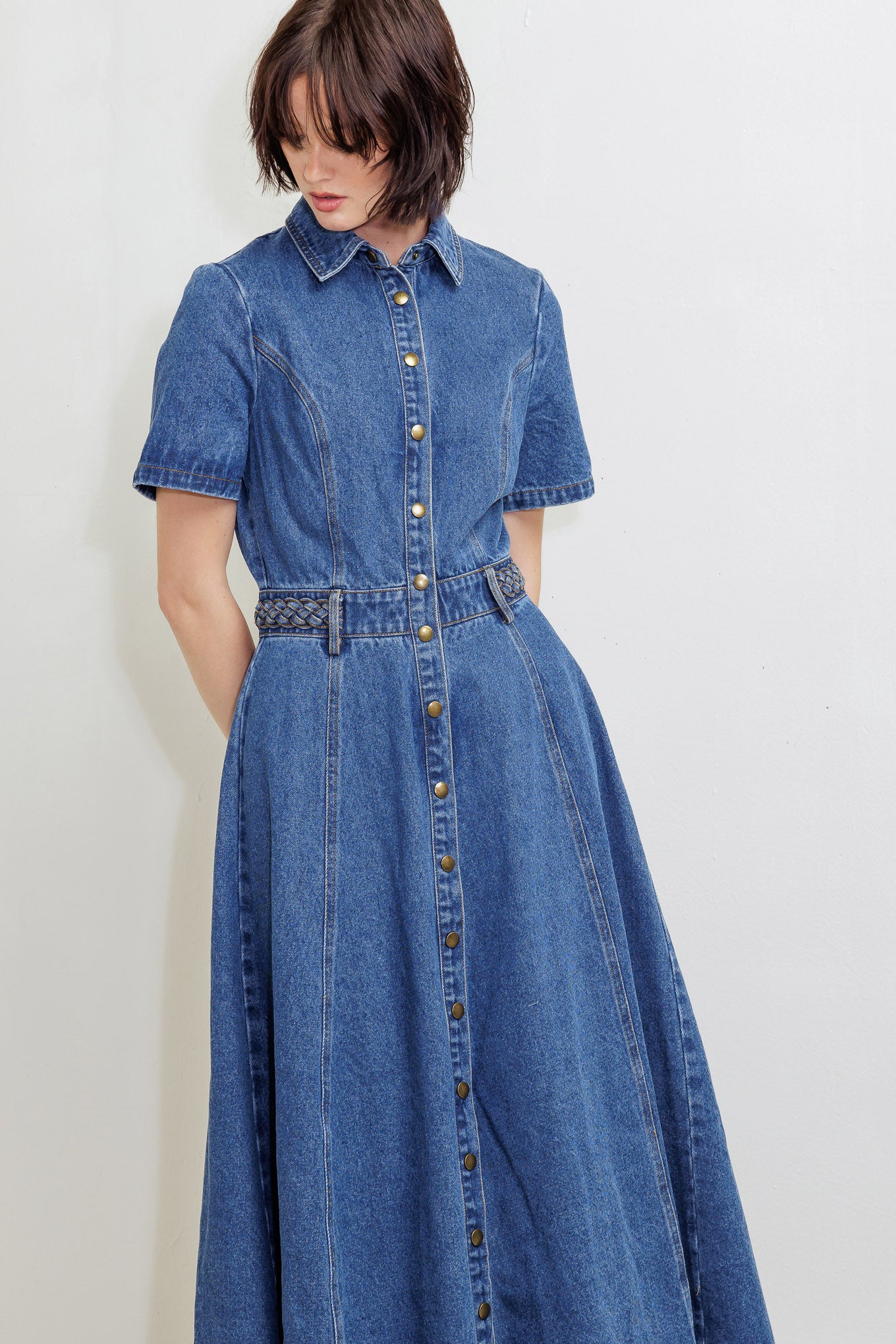 A washed denim midi dress featuring collar, short sleeve, button down, braided waistband and circle skirt