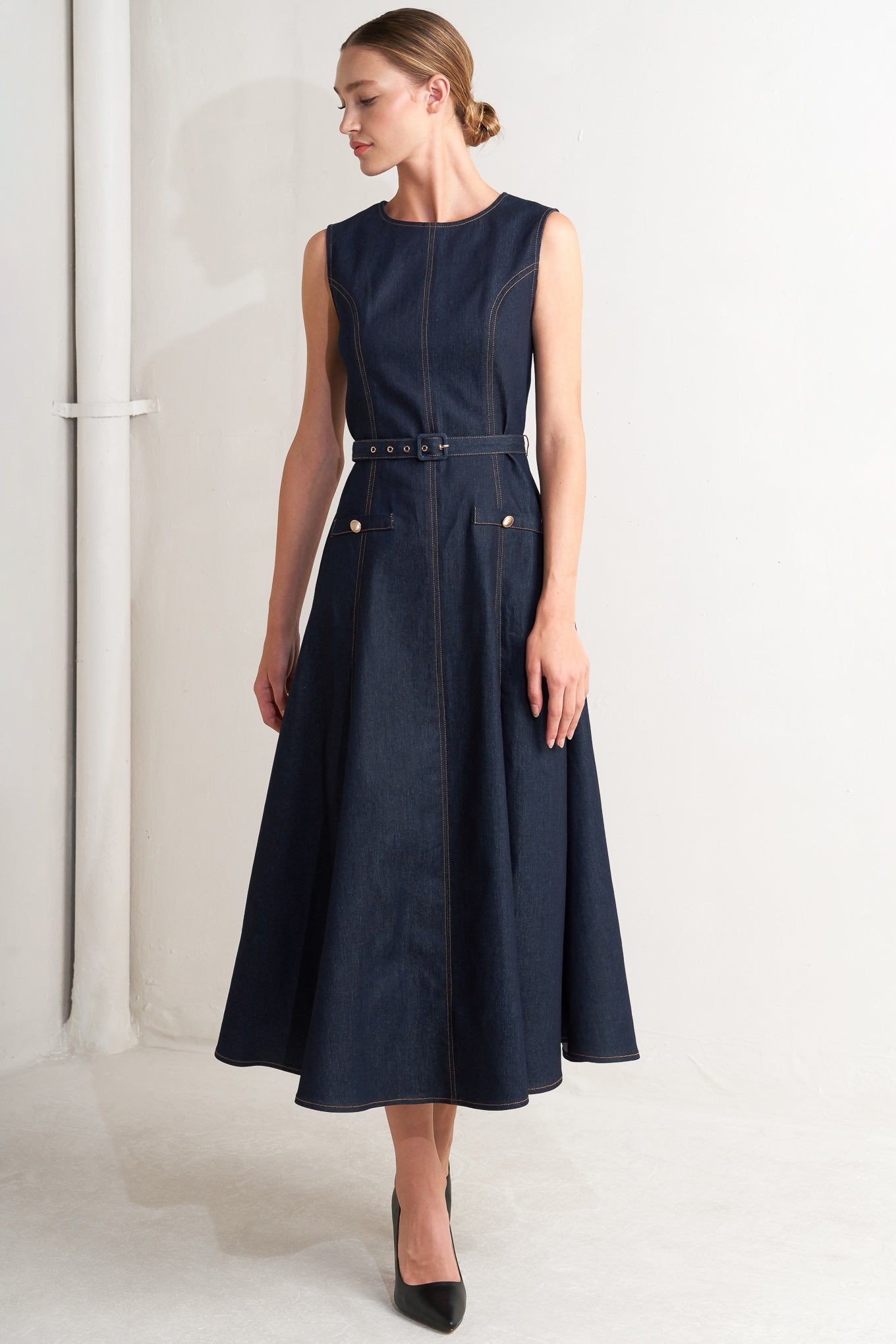 A denim midi dress featuring round neckline, sleeveless, self belt, circle skirt and back zipper closure
