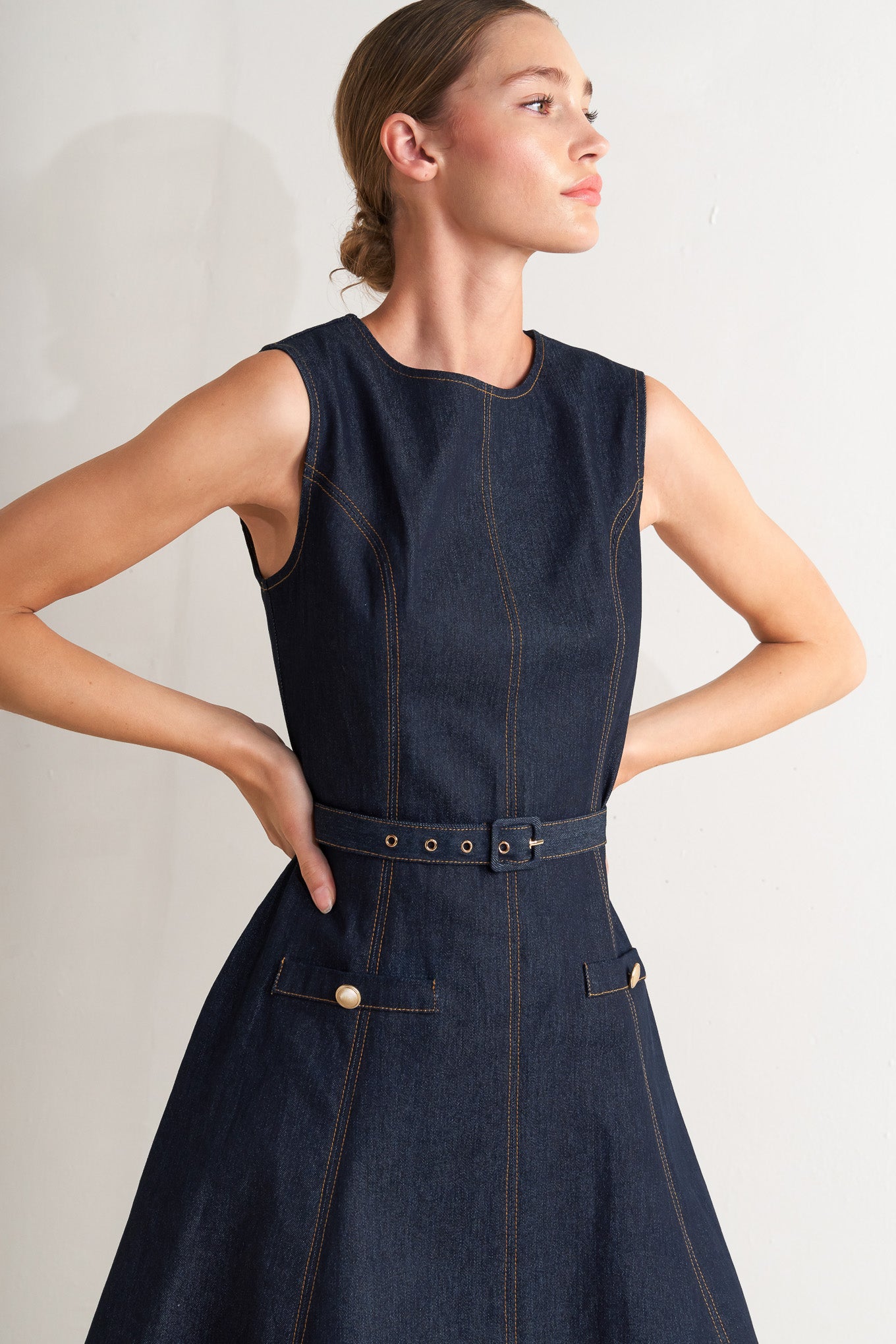 A denim midi dress featuring round neckline, sleeveless, self belt, circle skirt and back zipper closure