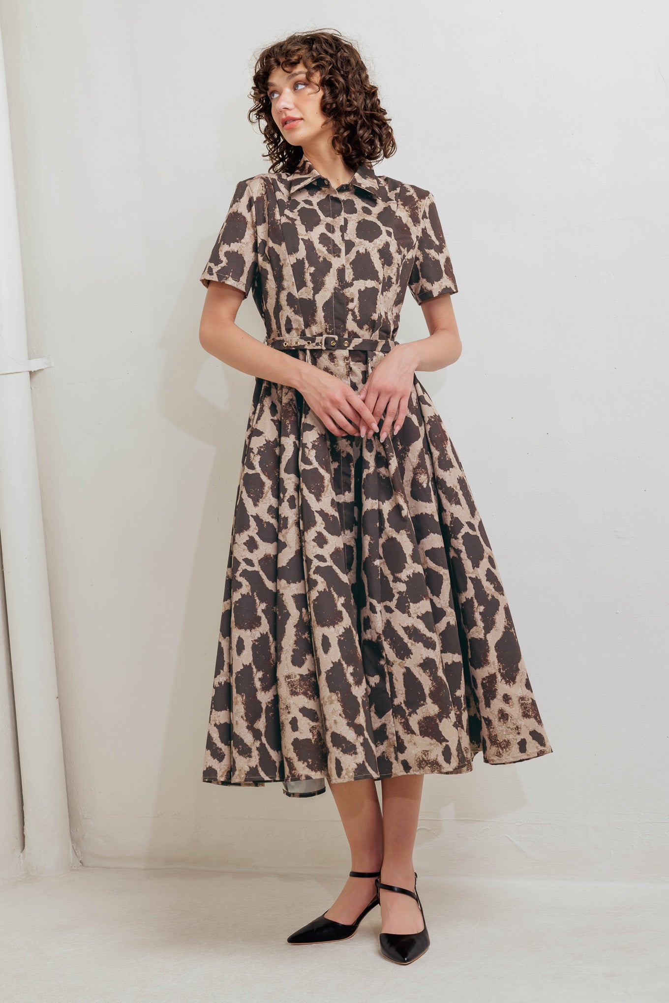 A printed woven midi dress featuring collar, short sleeve, hidden placket with button, self belt and circle skirt