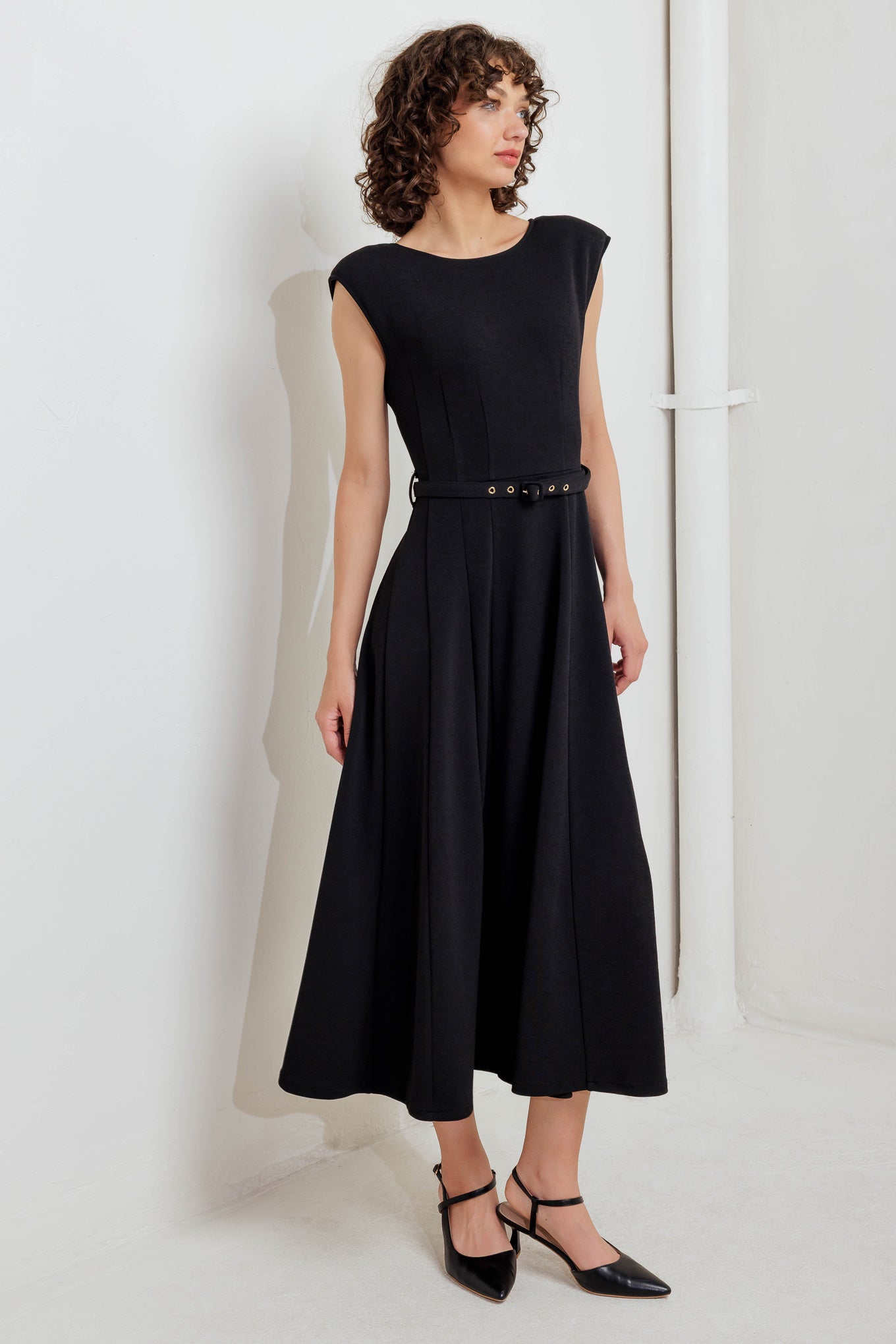 A solid woven midi dress featuring round neckline, drop shoulder, self belt, circle skirt, V back bodice and zipper closure