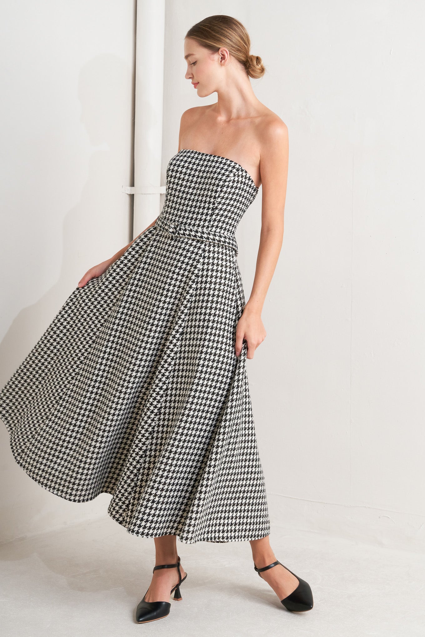 A woven houndstooth midi dress featuring strapless, self belt, full skirt and back zipper closure