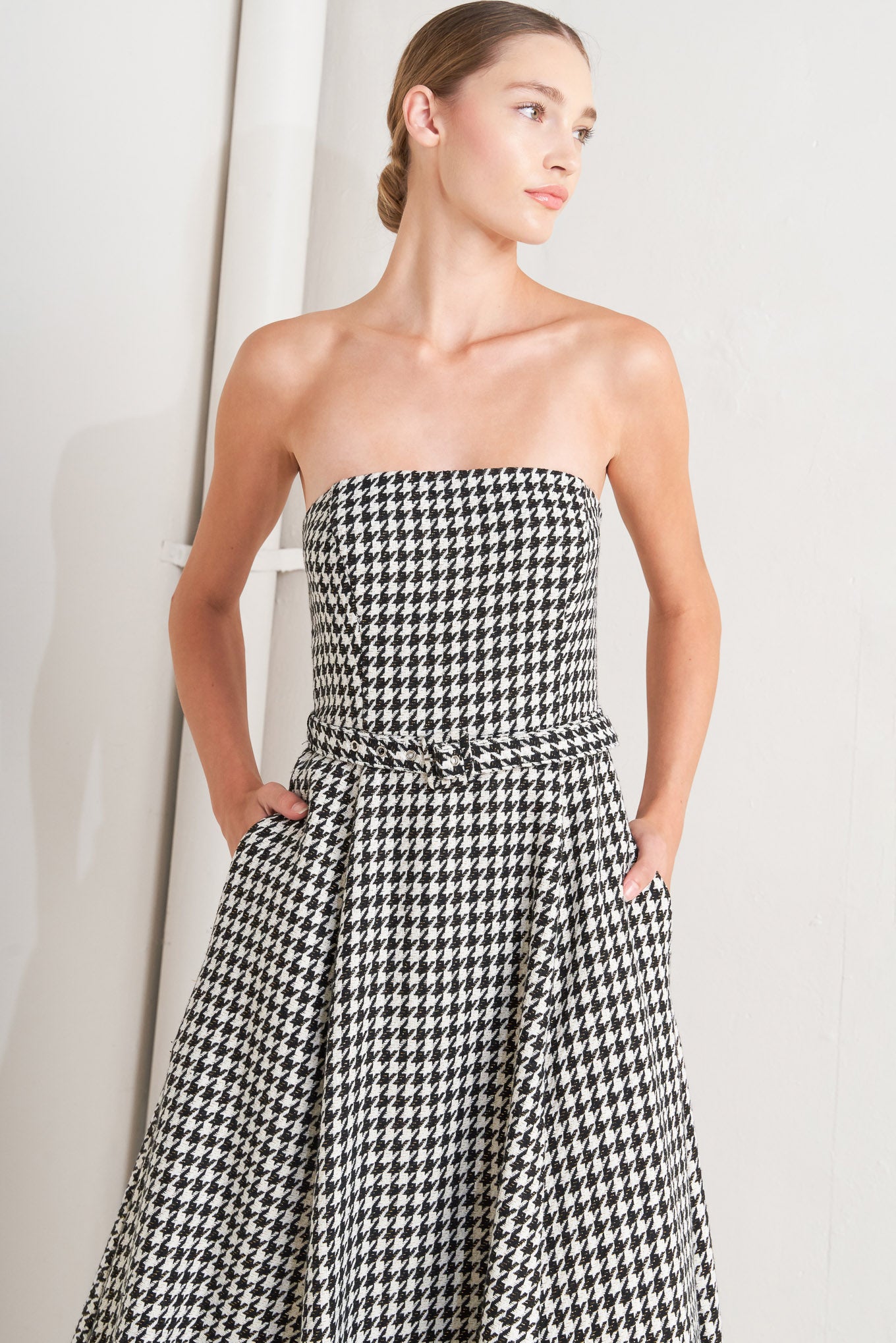 A woven houndstooth midi dress featuring strapless, self belt, full skirt and back zipper closure