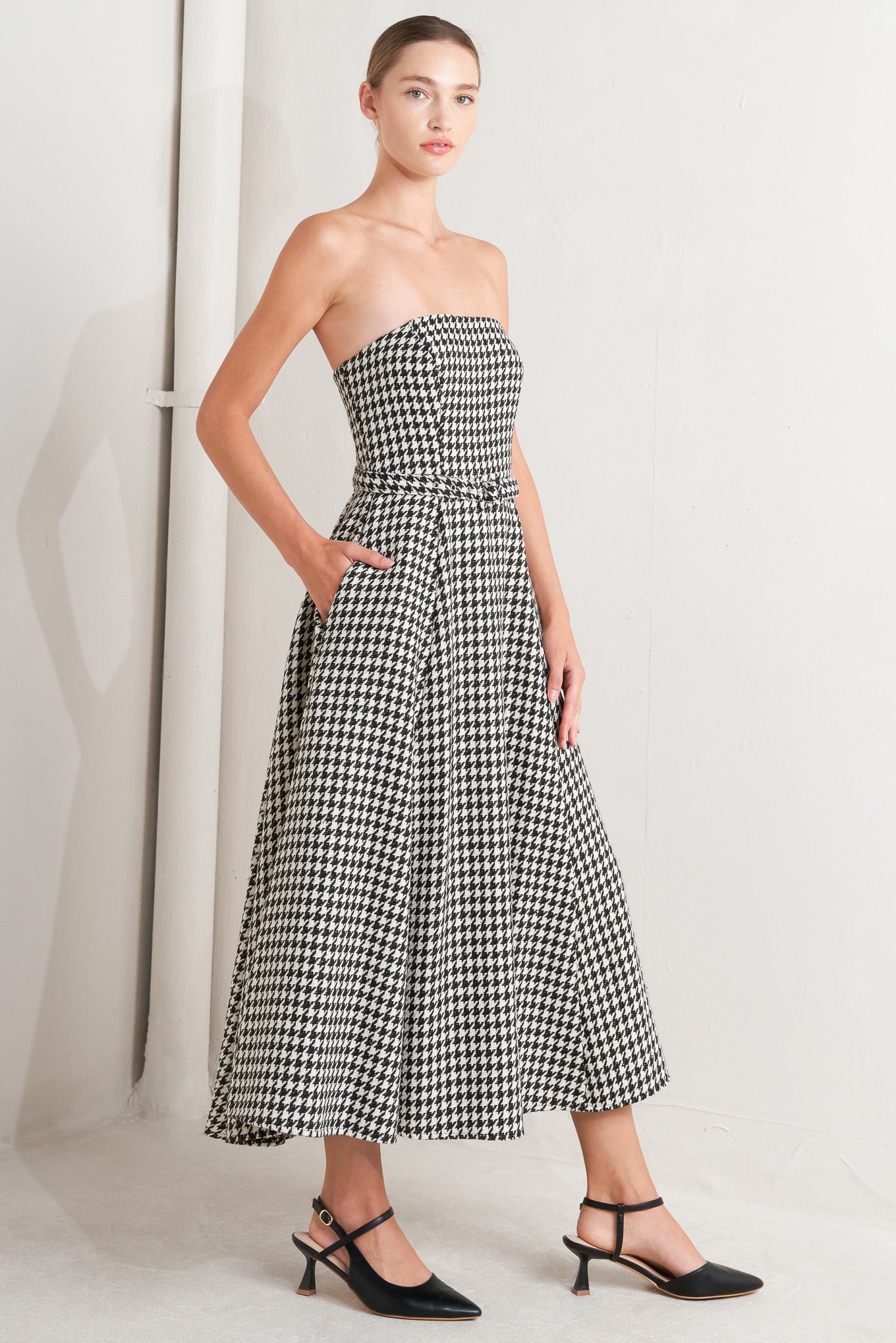 A woven houndstooth midi dress featuring strapless, self belt, full skirt and back zipper closure