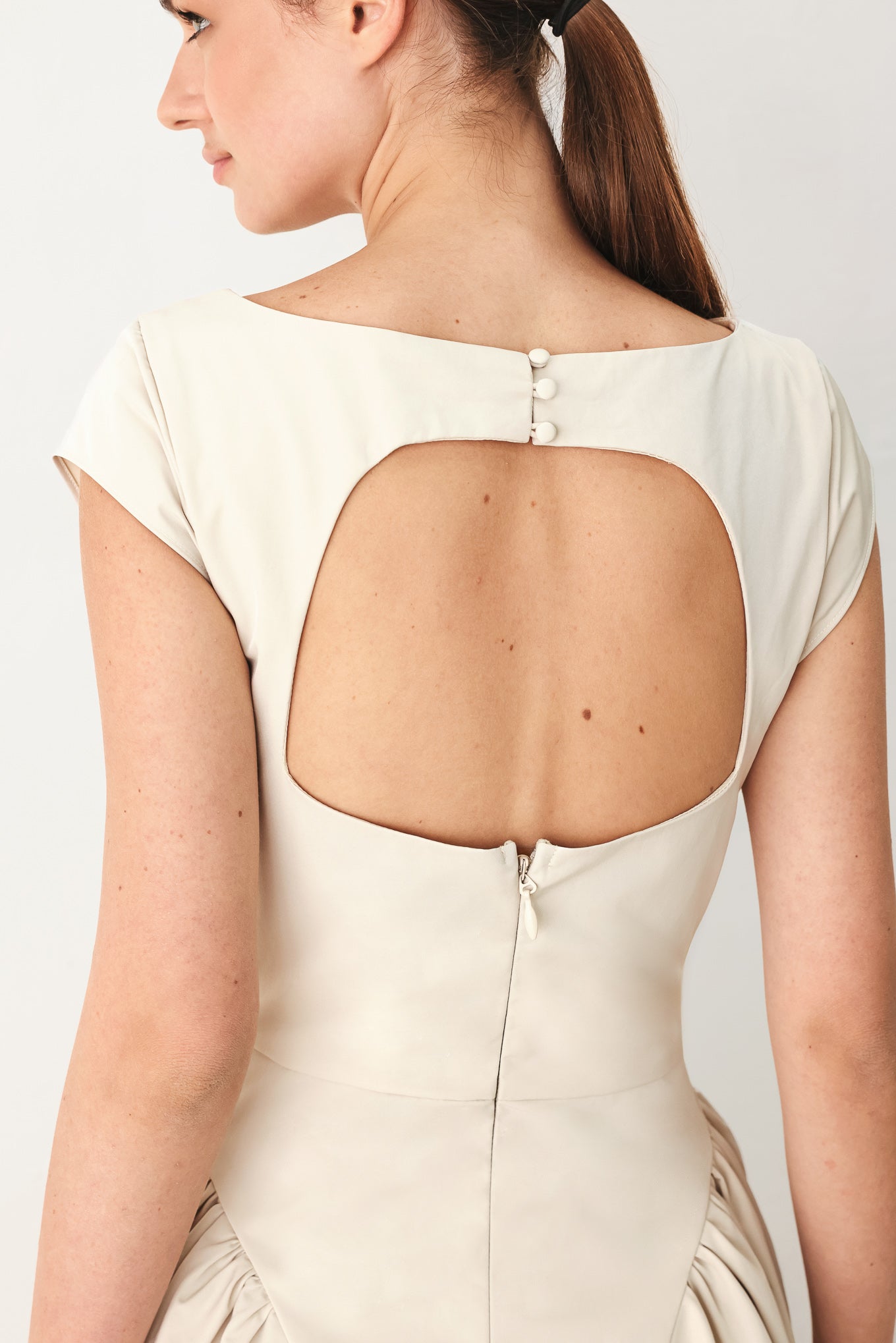 Woman wearing a solid light taupe woven midi dress featuring wide neckline, cap sleeve, side shirred full skirt, back cut out and button zipper closure | FREEMARKET