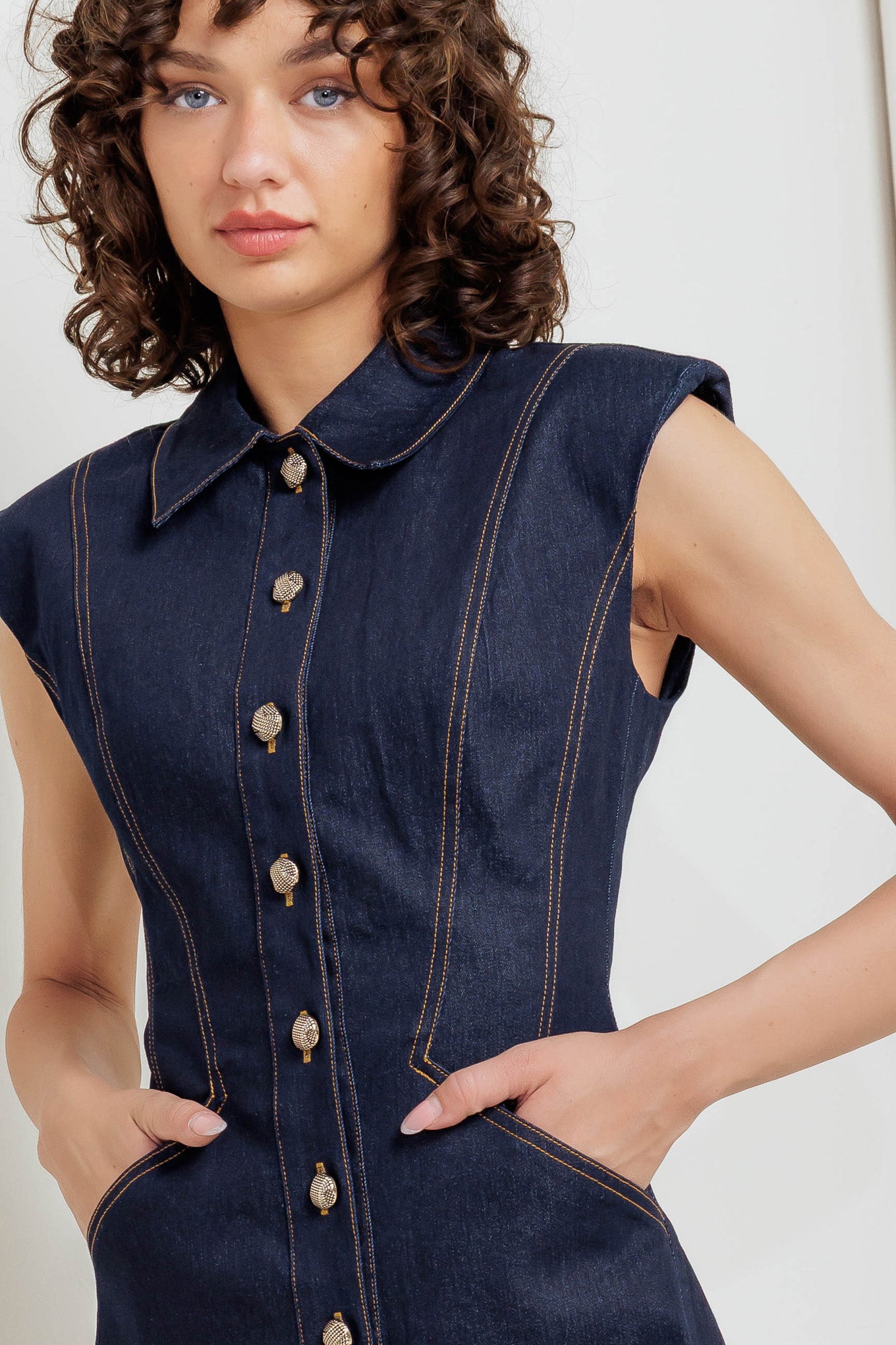A denim mini dress featuring collar, sleeveless and front button down closure
