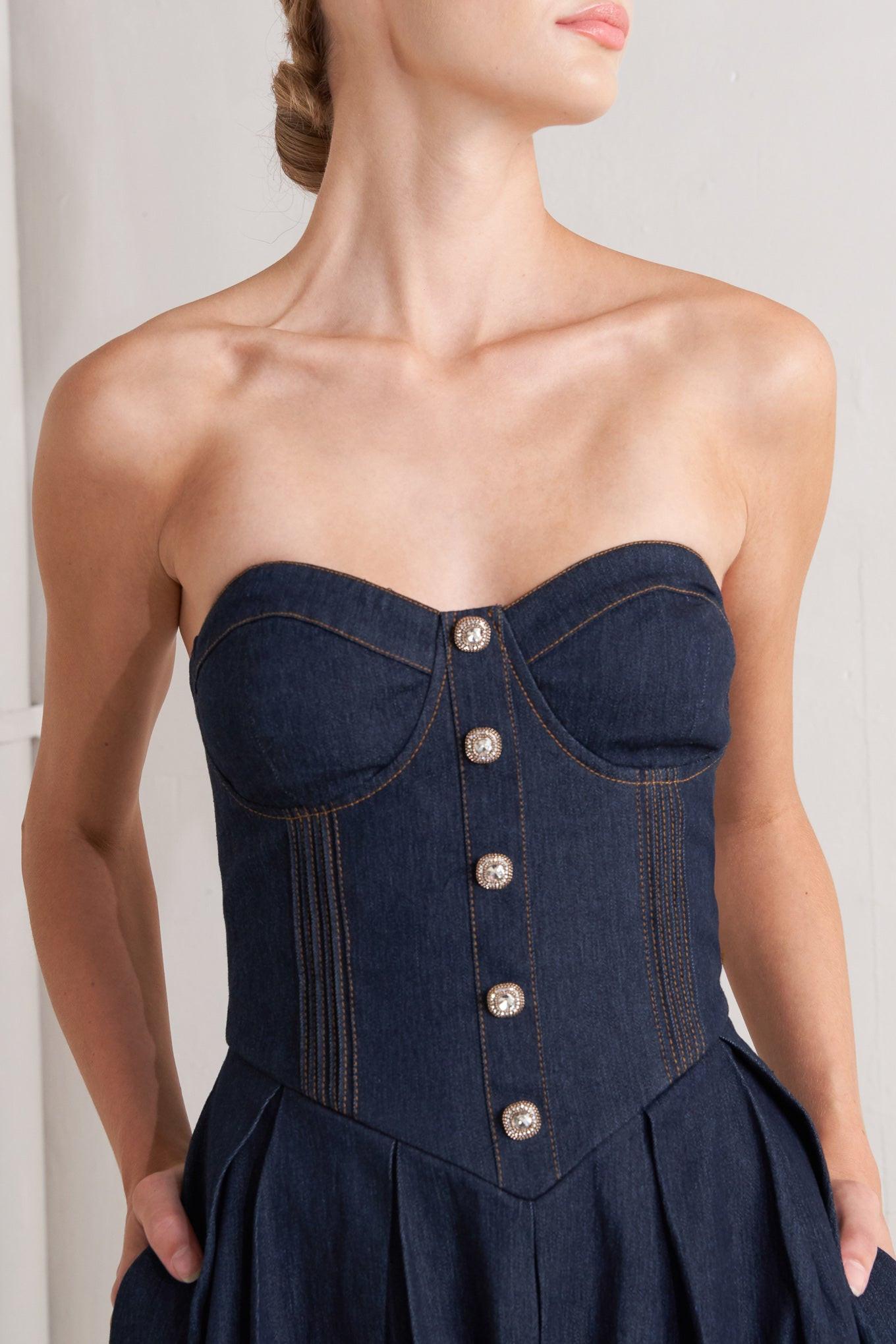 A denim midi dress featuring strapless sweetheart neckline, bustier bodice with button detail, basque waist, full skirt and back zipper closure