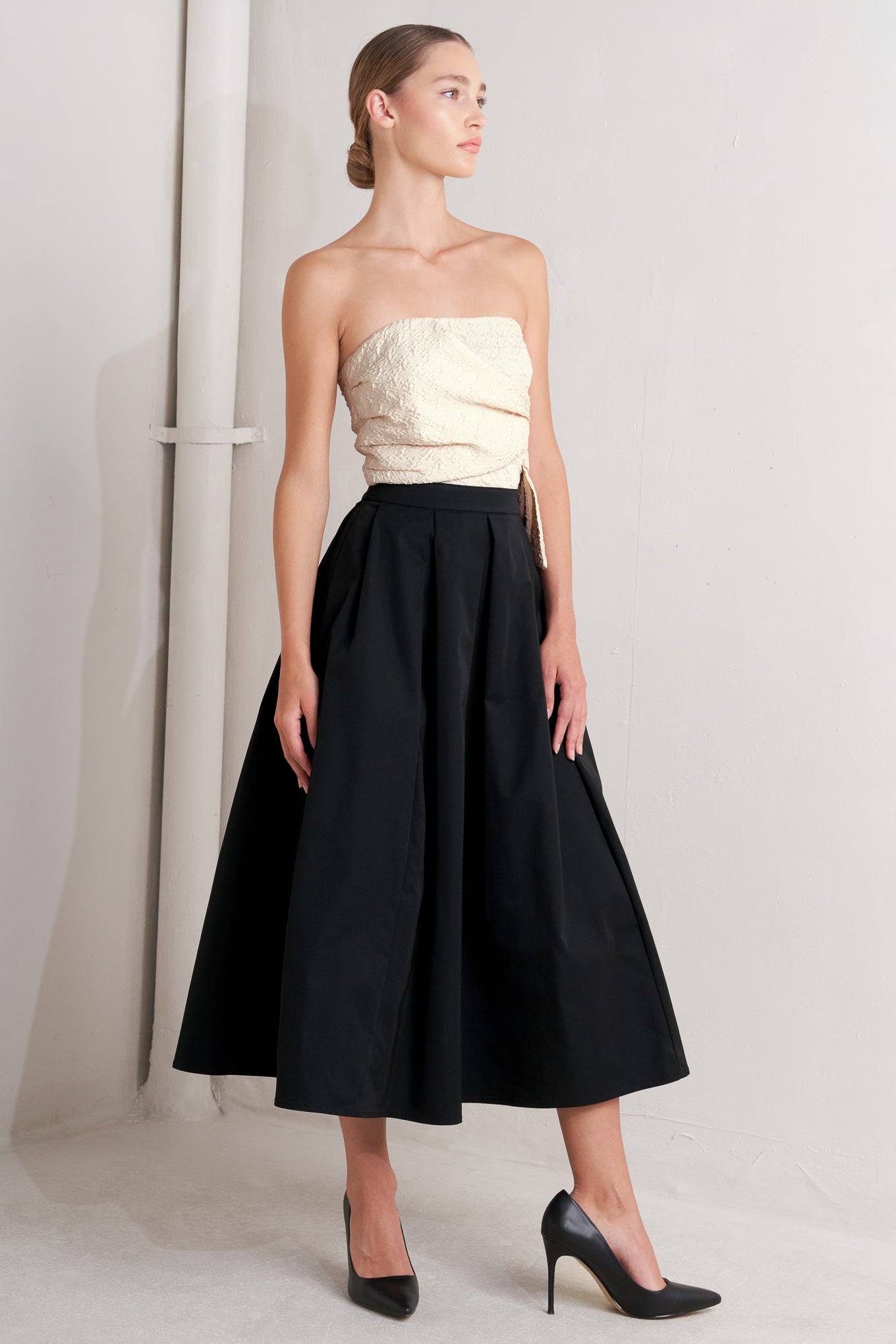 A solid woven midi dress featuring strapless textured woven bodice, full skirt and back zipper closure