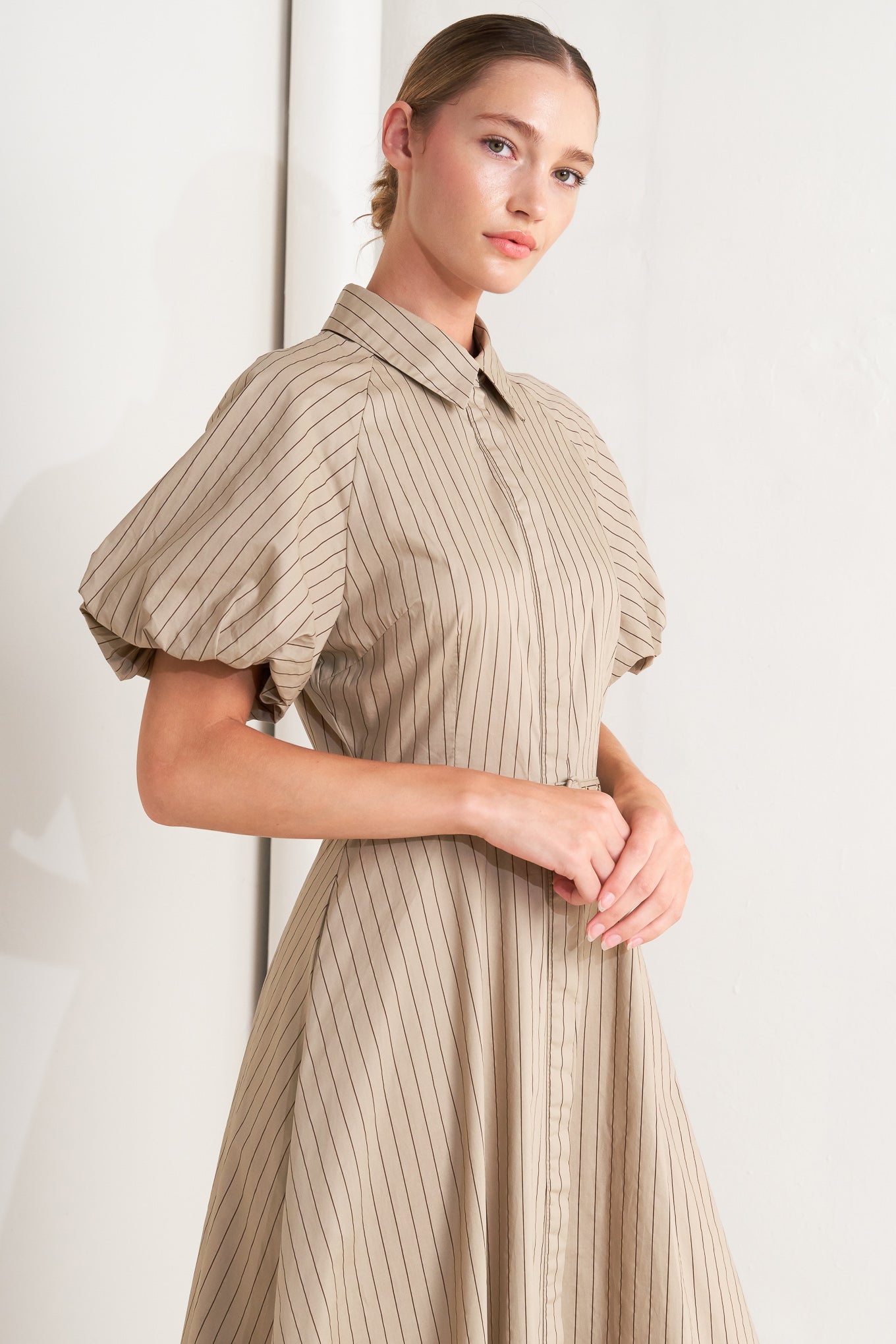 A striped woven midi dress featuring collar, raglan short puff sleeve, hidden button down, self belt and circle skirt