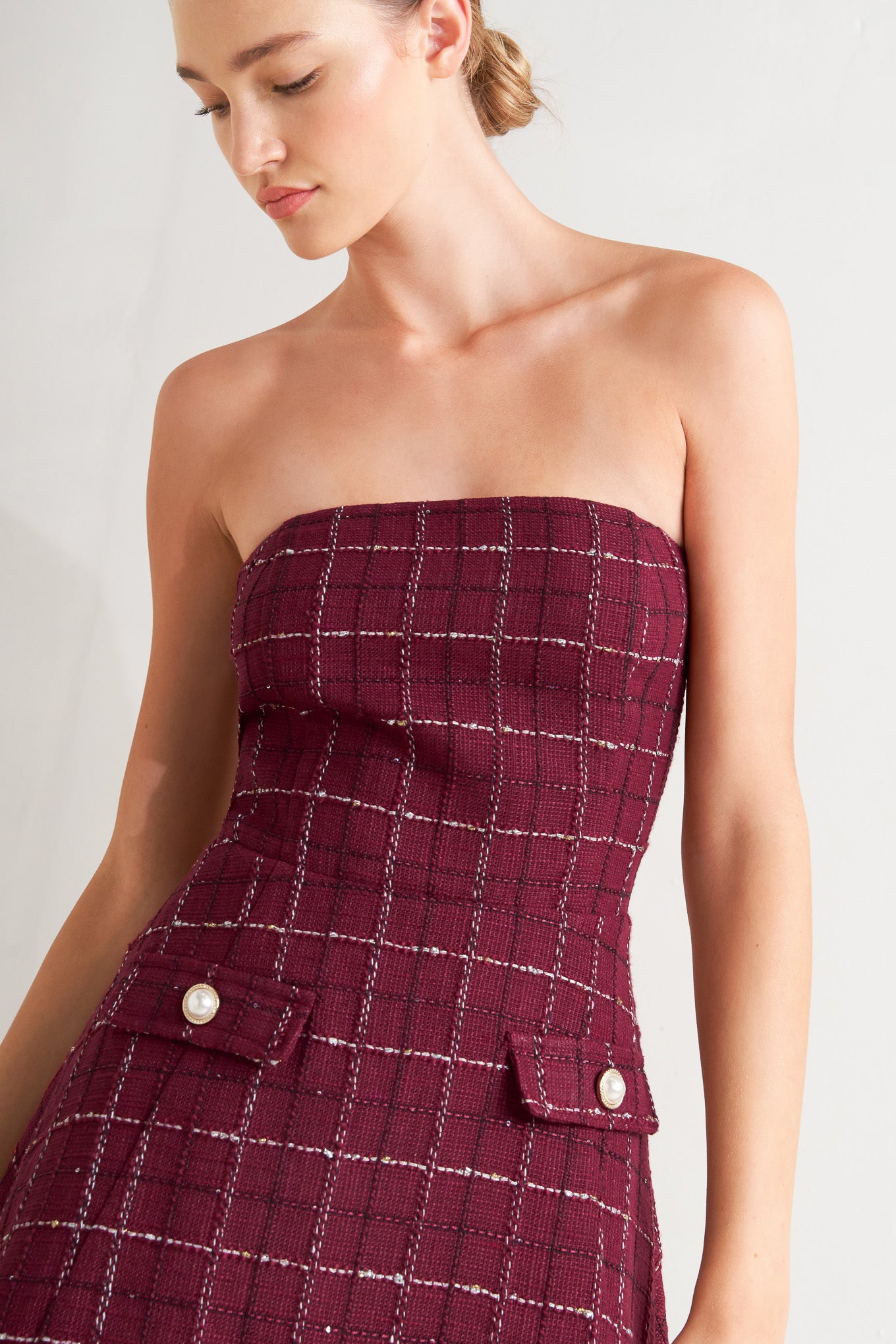 A solid woven midi dress featuring strapless textured woven bodice, full skirt and back zipper closure