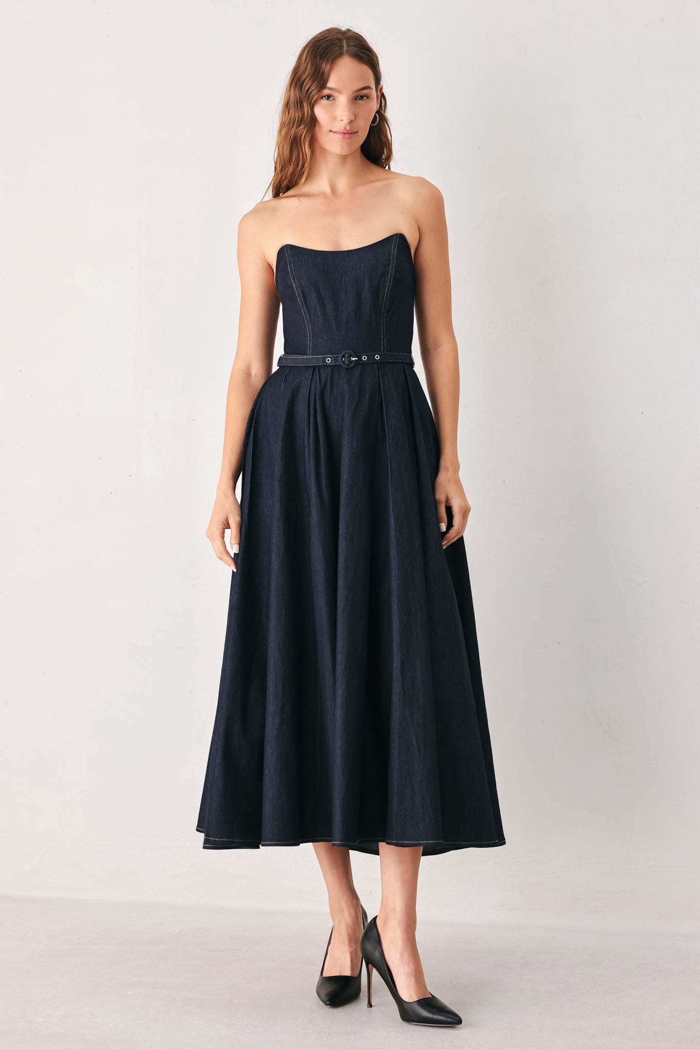 A woman wearing a strapless midi dress in dark navy blue with a matching belt | FREEMARKET