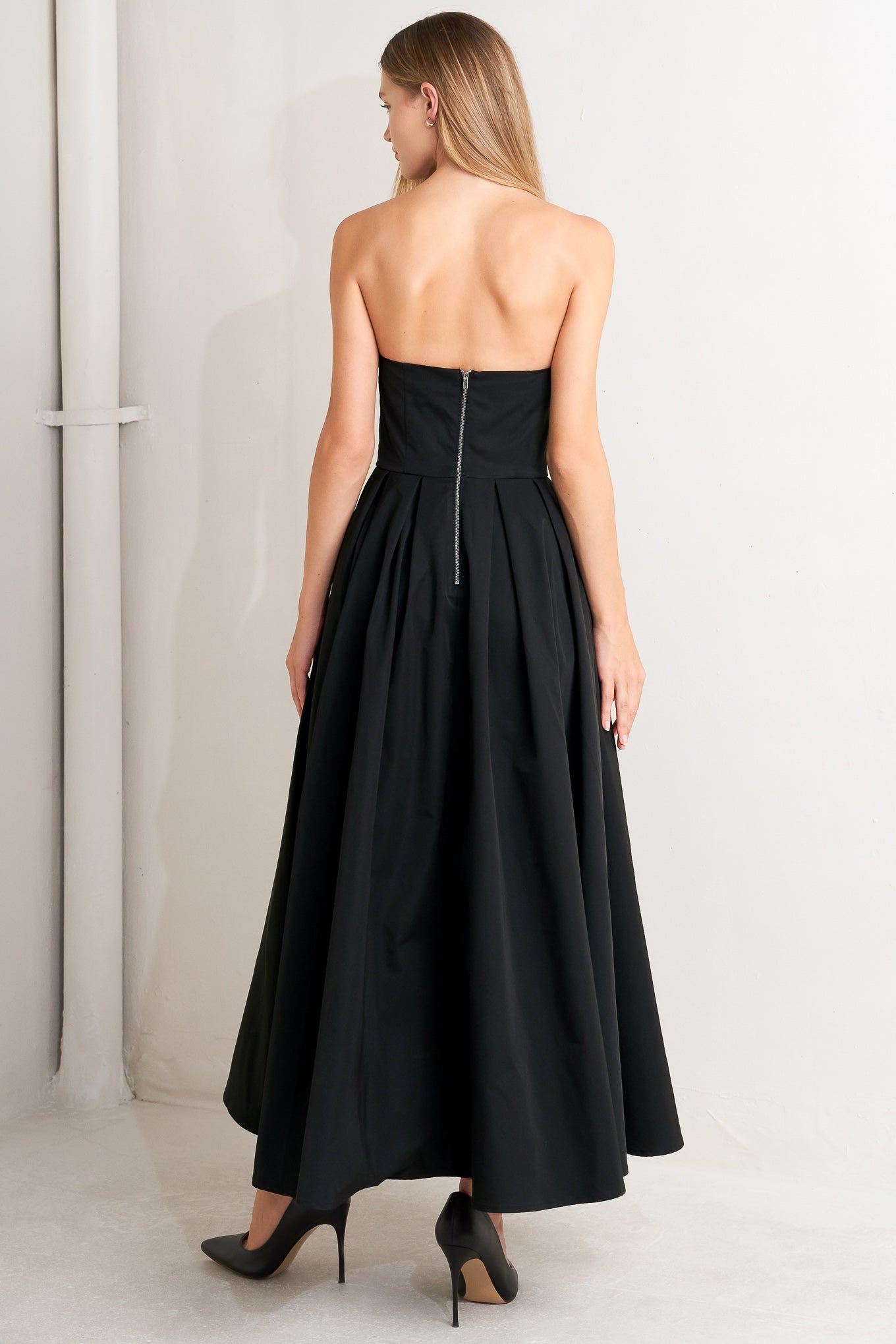 A solid woven midi dress featuring strapless with pointed side neckline, full skirt and back zipper closure