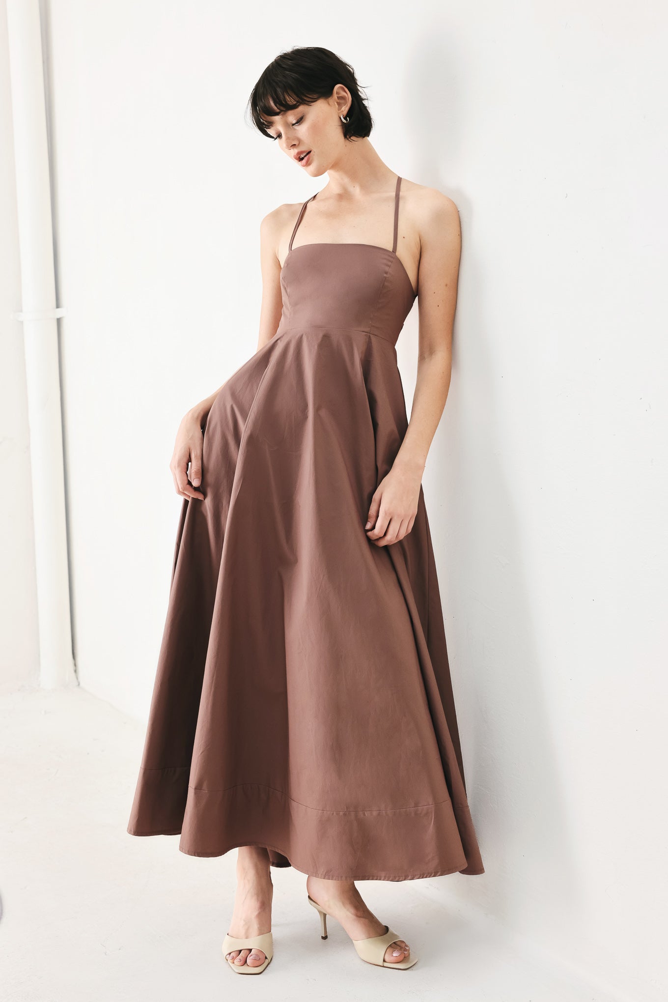 Woman wearing a brown midi dress featuring straight neckline, circle skirt and bare back with lace up tie closure | FREEMARKET | Flying Tomato