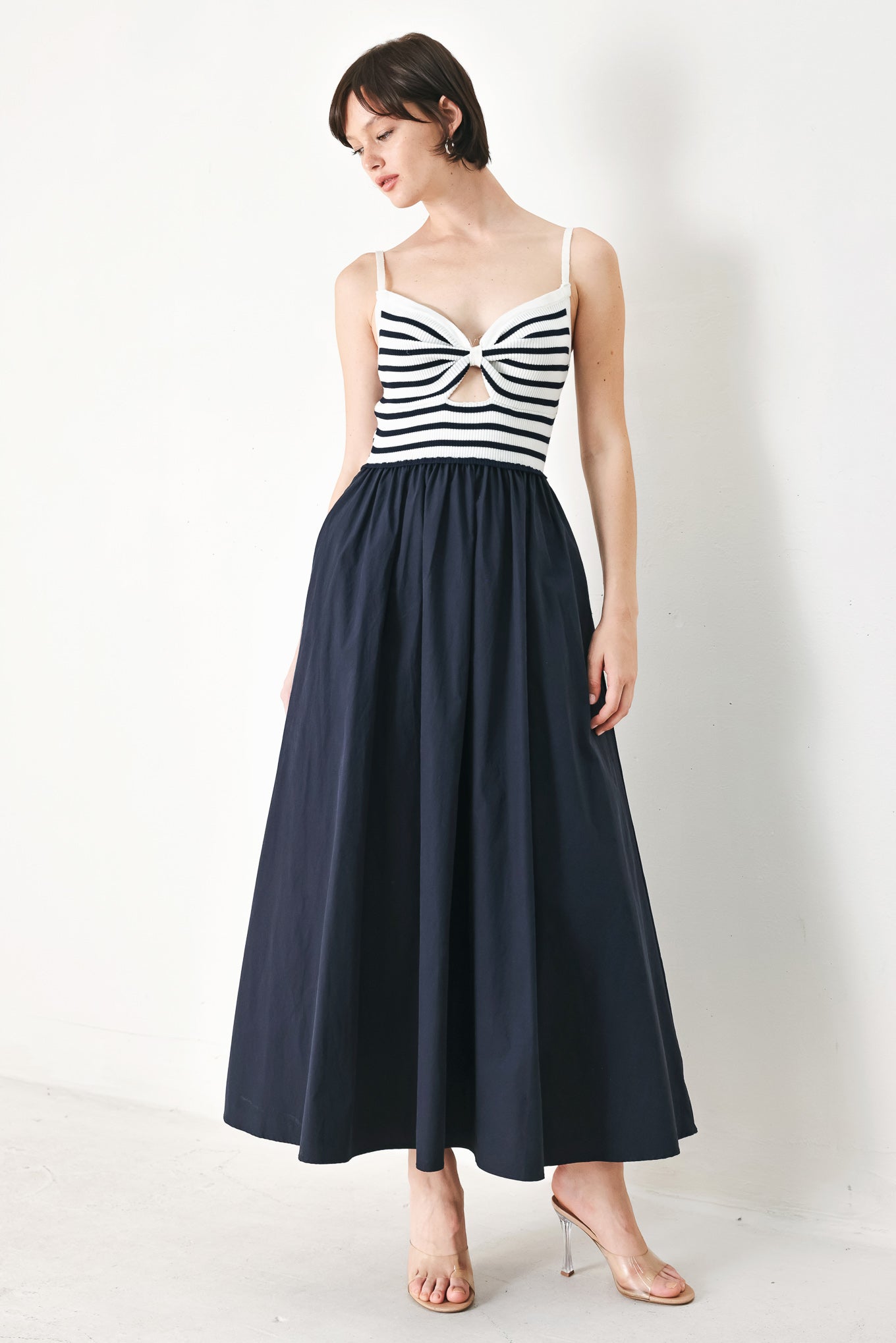 A midi dress featuring sweater knit top with cinched front bodice and cut out, straps and solid woven full skirt