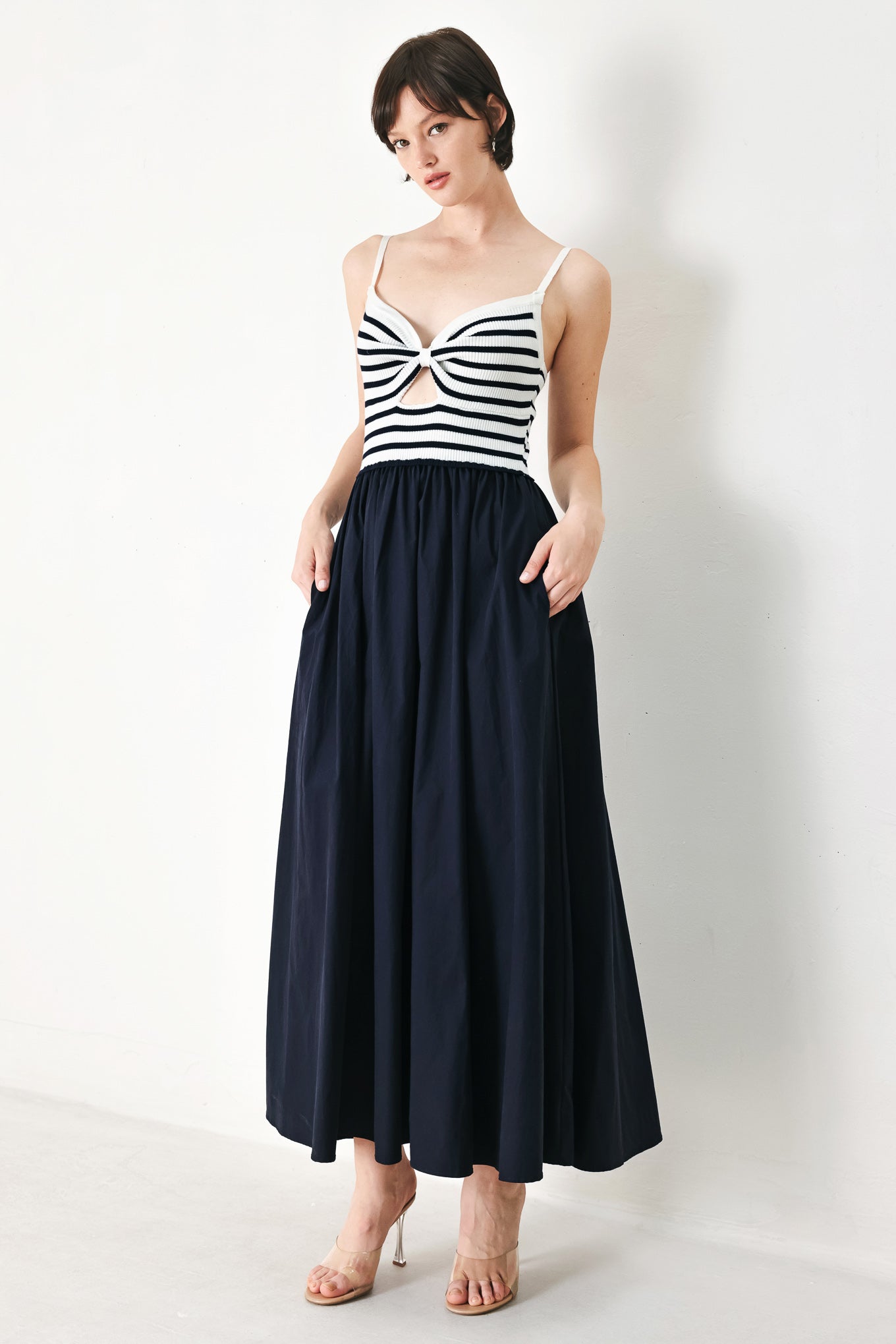 A midi dress featuring sweater knit top with cinched front bodice and cut out, straps and solid woven full skirt