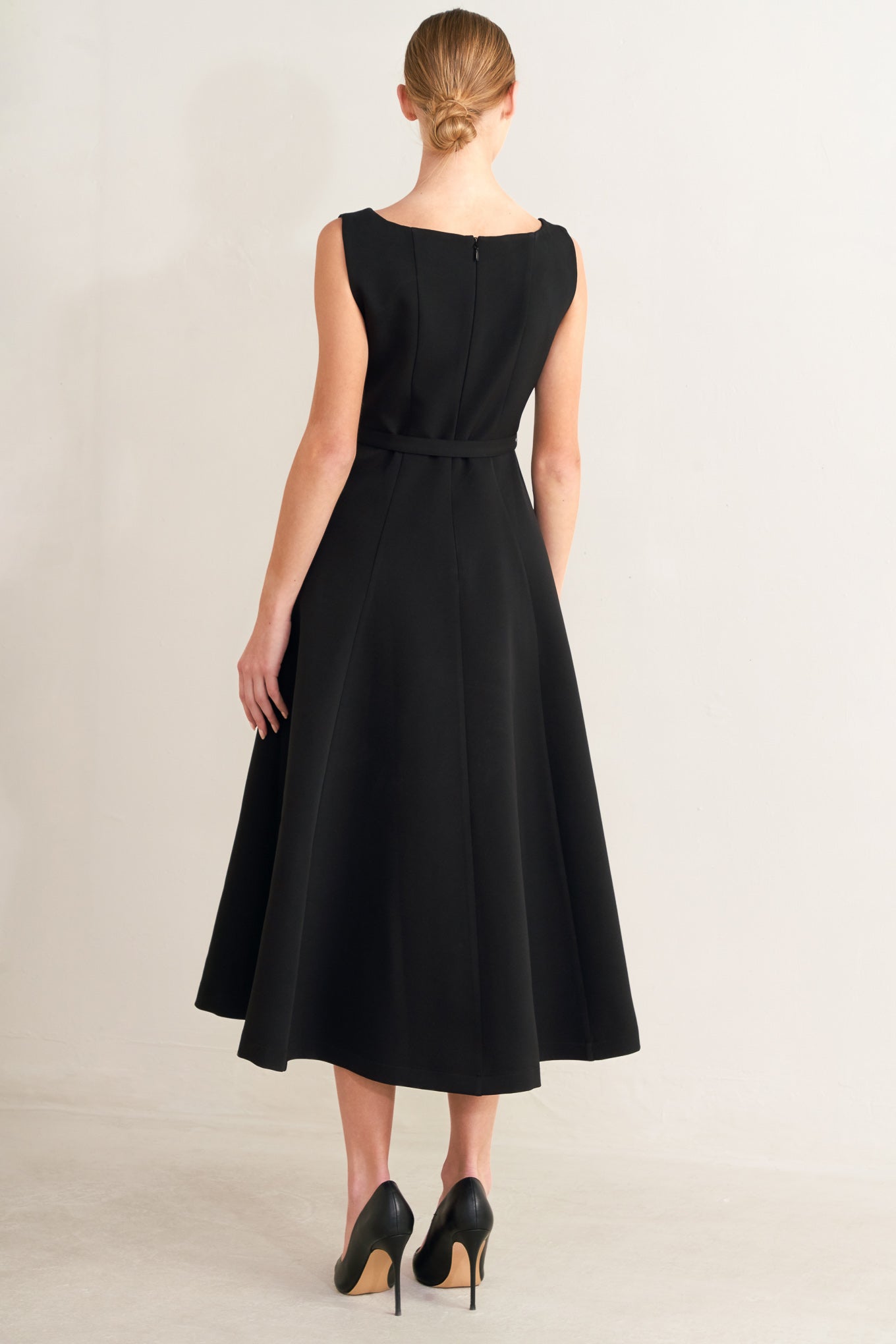 Black dress worn by a model on a plain background