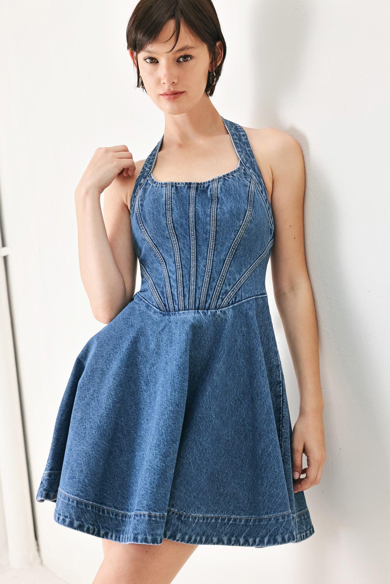 A washed denim mini dress featuring halter neckline with back button closure, full circle skirt bare back with zipper closure