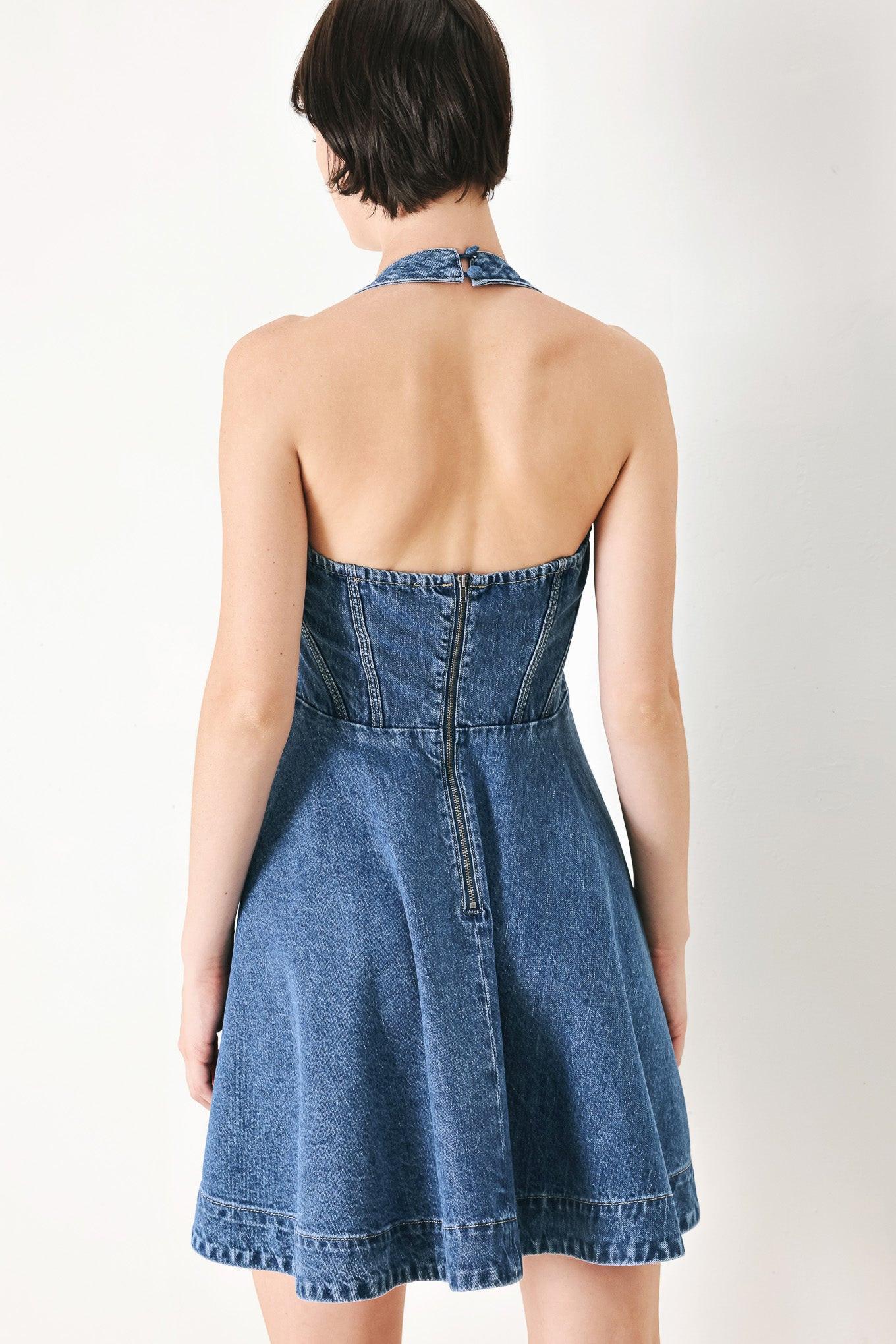 A washed denim mini dress featuring halter neckline with back button closure, full circle skirt bare back with zipper closure