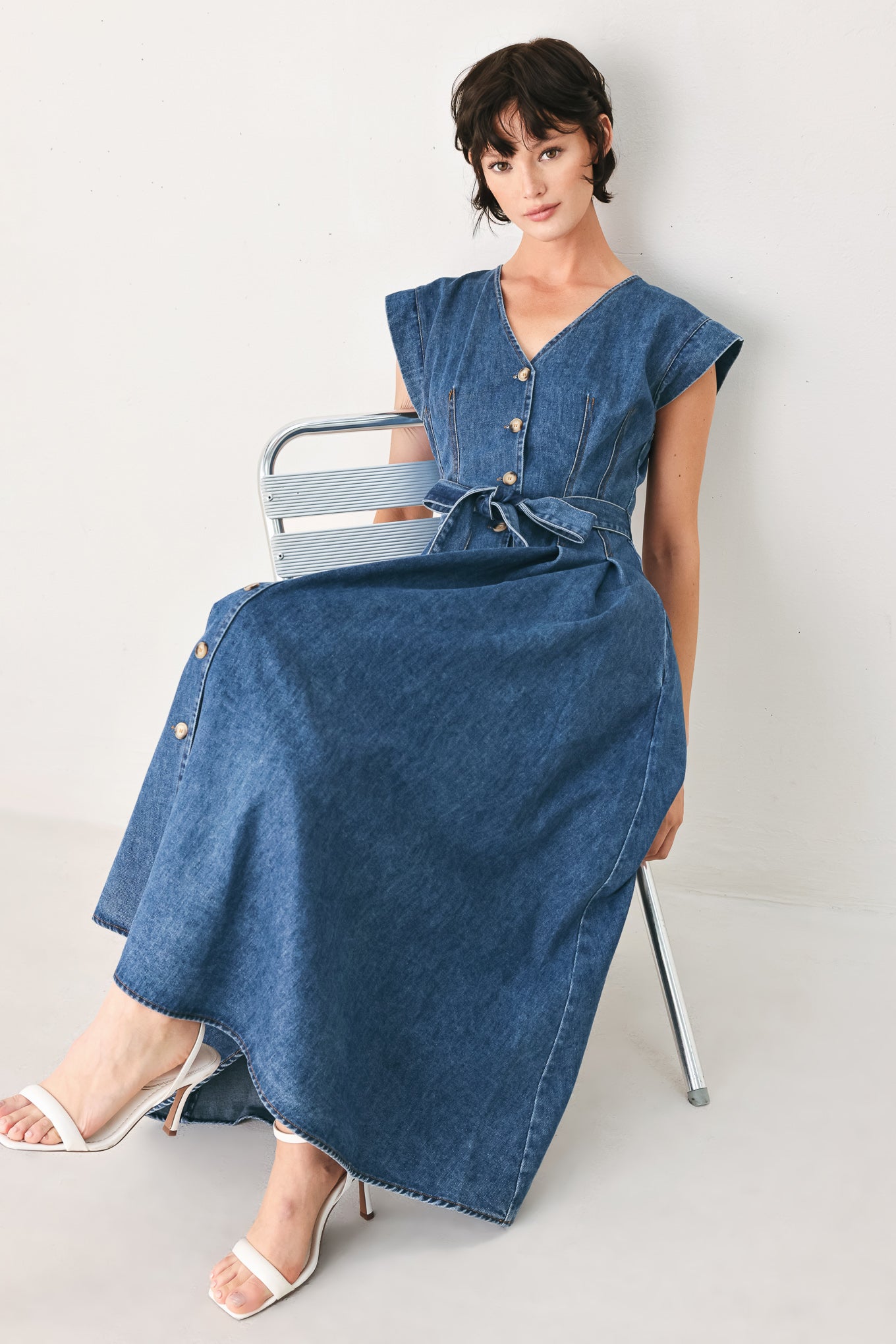 Woman wearing a short sleeve blue denim midi dress with V neckline, front button down, corset waist, self sash tie and full skirt | FREEMARKET
