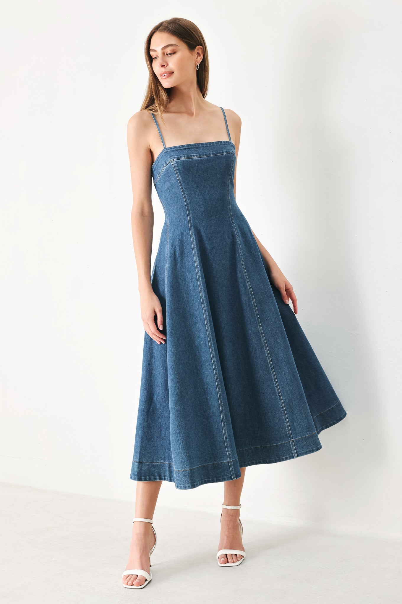 Woman wearing a blue denim midi dress featuring straight neckline, straps, circle skirt and back zipper closure | FREEMARKET | Flying Tomato