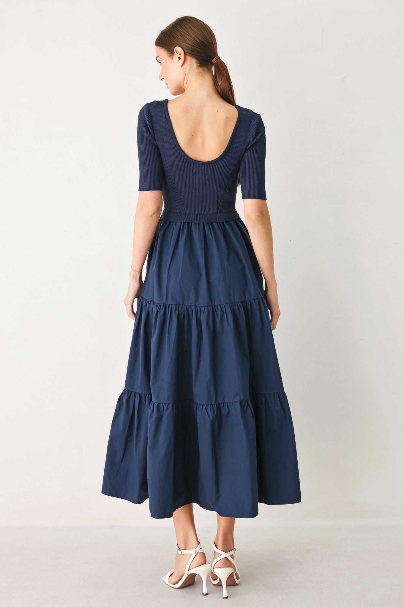 Woman wearing a solid sweater knit and woven mix navy blue midi dress featuring square neckline, short sleeve and tier skirt | FREEMARKET