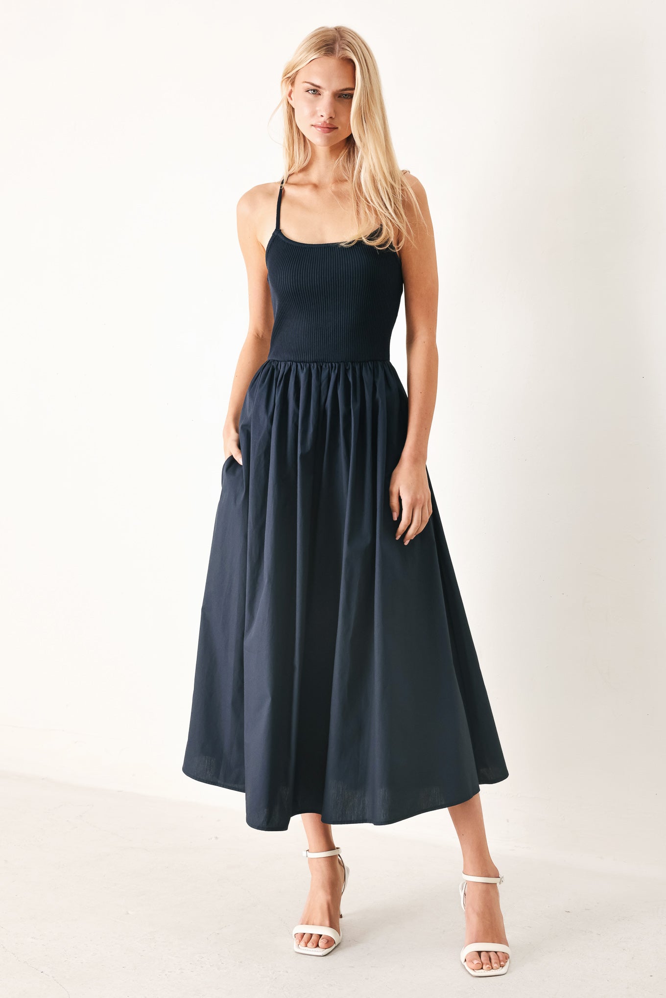 Woman wearing a navy sleeveless midi dress featuring ribbed sweater knit tank top, solid woven skirt, bare back with lace up tie detail | FREEMARKET