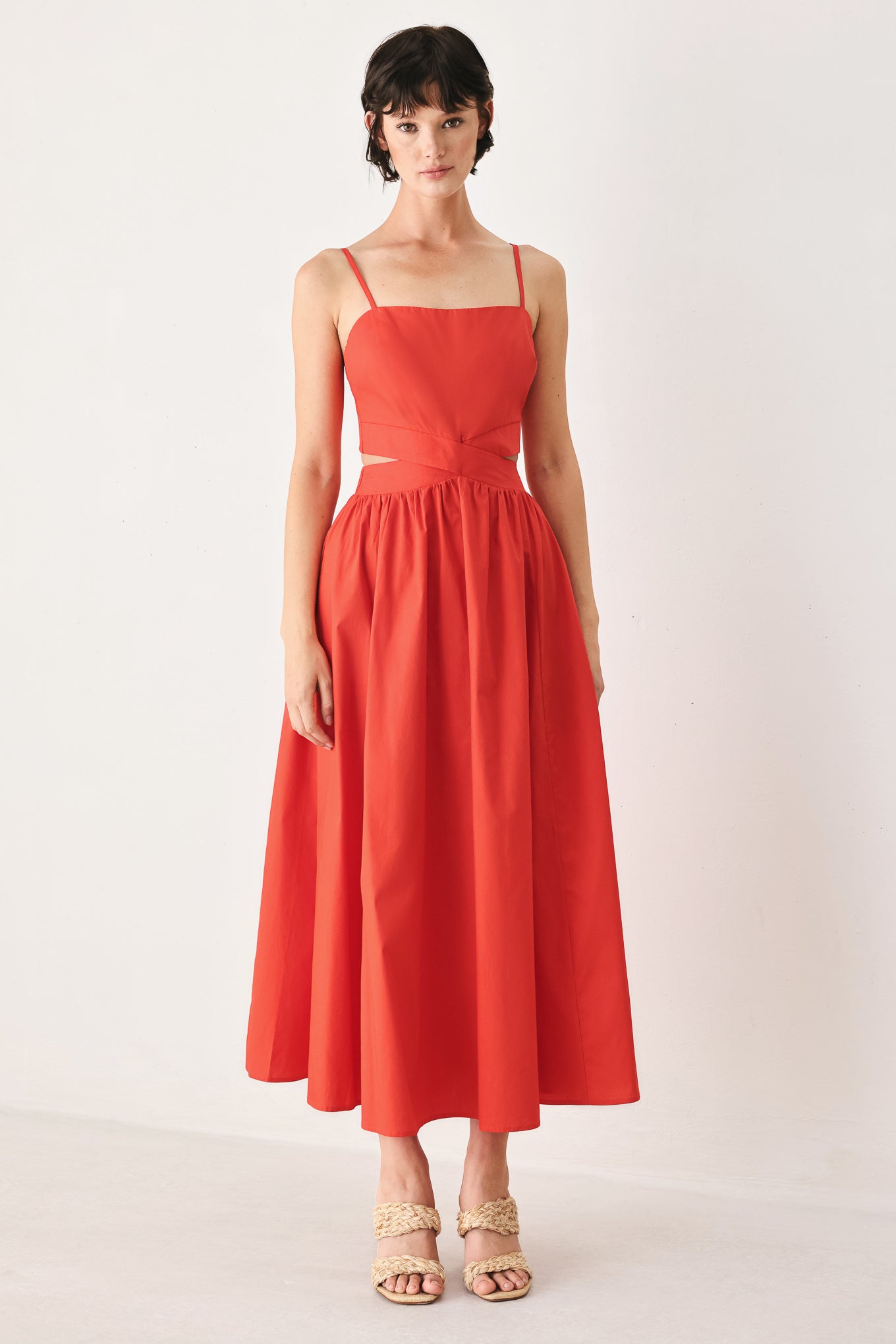 Woman wearing a red midi dress featuring straight neckline, straps, waist cutout, full skirt, and tie detail | FREEMARKET