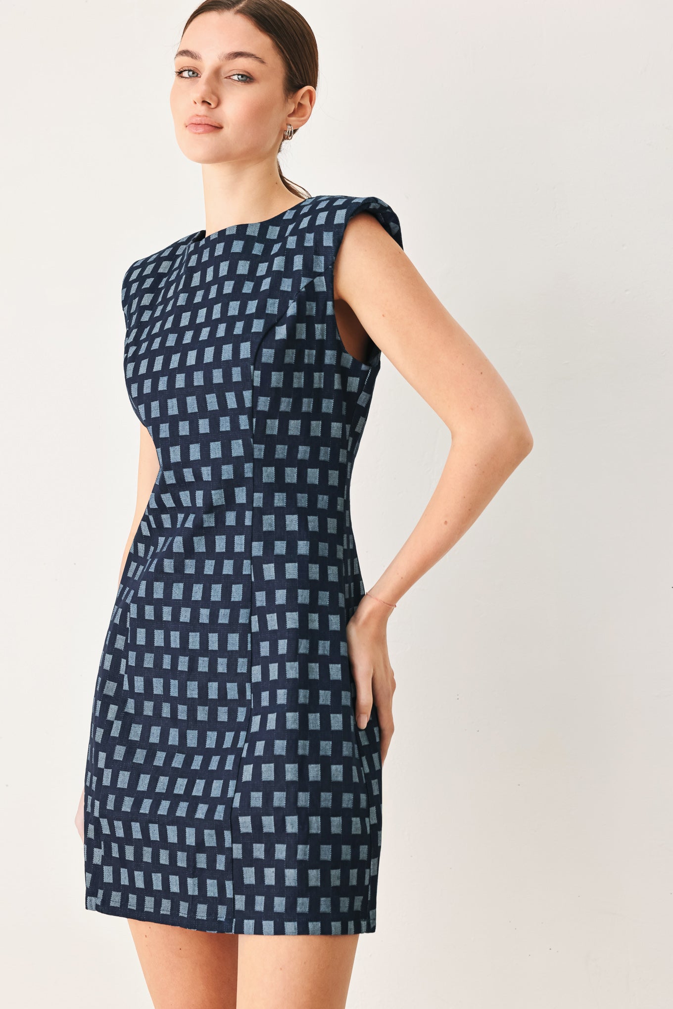 Woman wearing a denim navy patterned jacquard denim mini dress with round neckline, sleeveless and back zipper closure | Flying Tomato