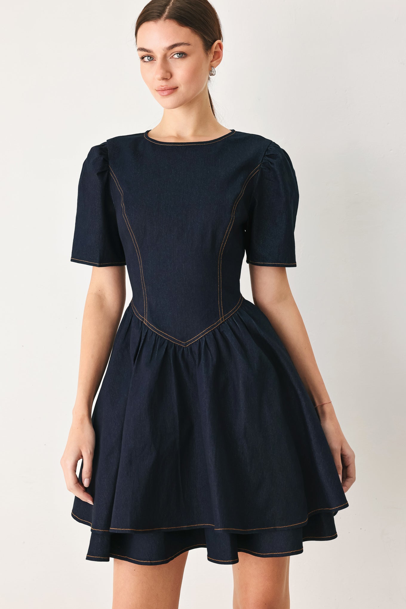 Woman wearing a dark denim navy blue mini dress featuring round neckline, short puff sleeve, basque waist, double layer skirt and back zipper closure | FREEMARKET