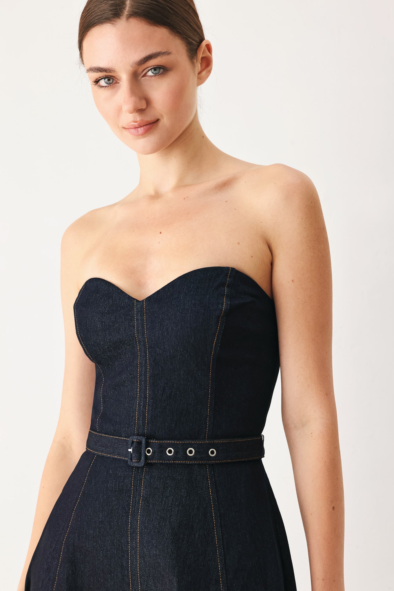 Woman wearing a dark denim strapless midi dress featuring a sweetheart neckline, self belt, circle skirt and back zipper closure | FREEMARKET