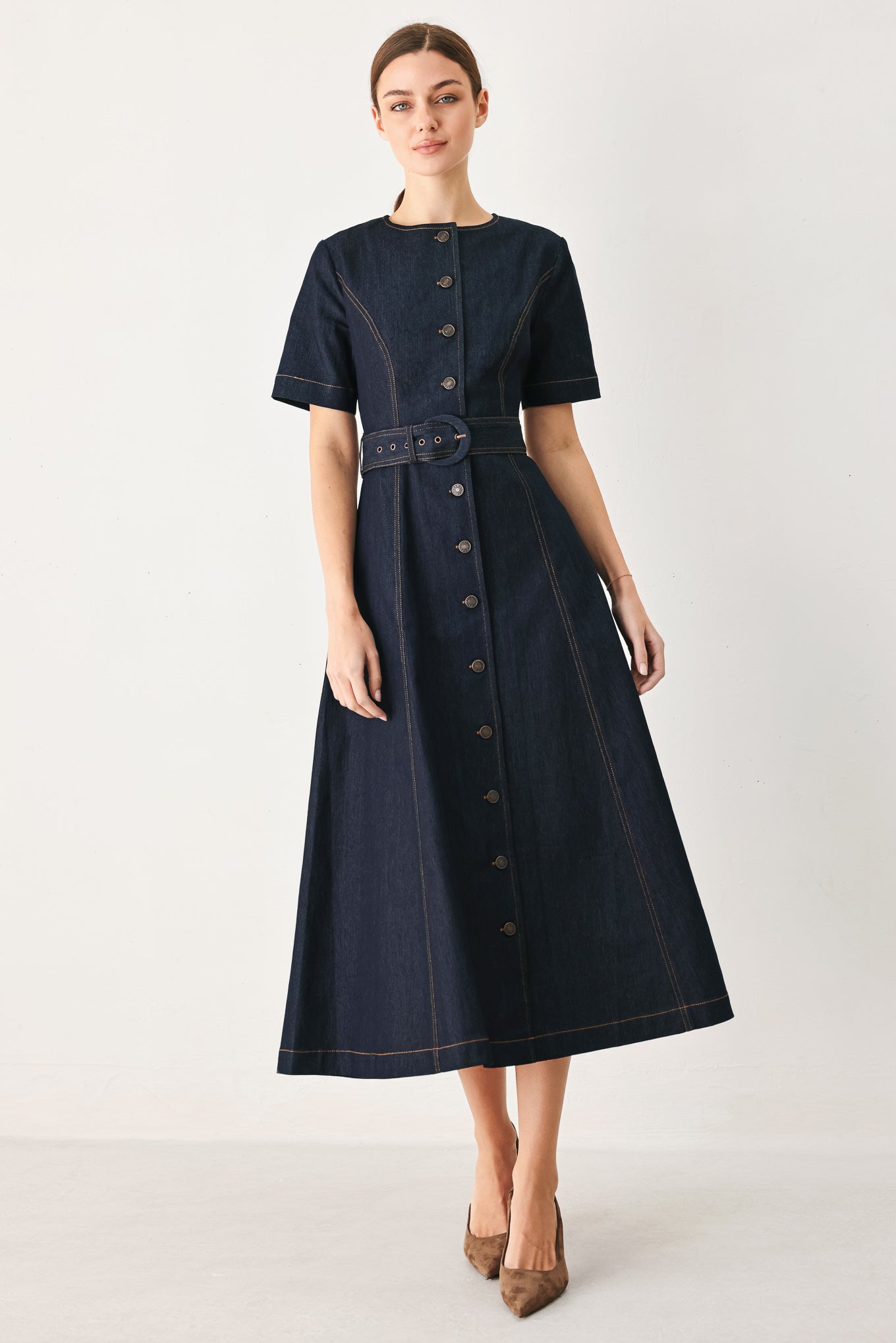 Woman wearing a dark blue dress with buttons on a white background
