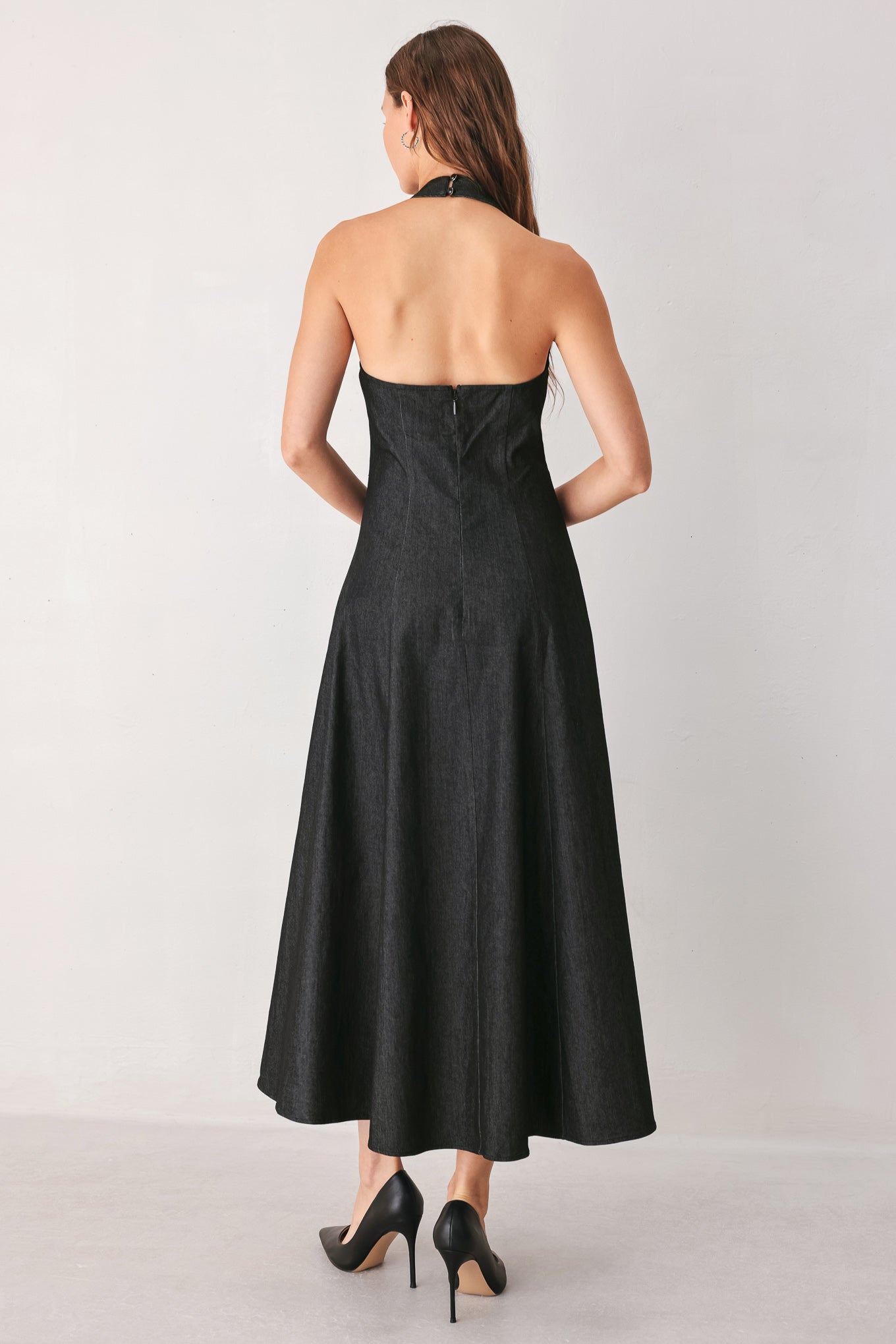 A woman modeling a sleeveless black midi dress with a high mock neck and flared skirt | FREEMARKET