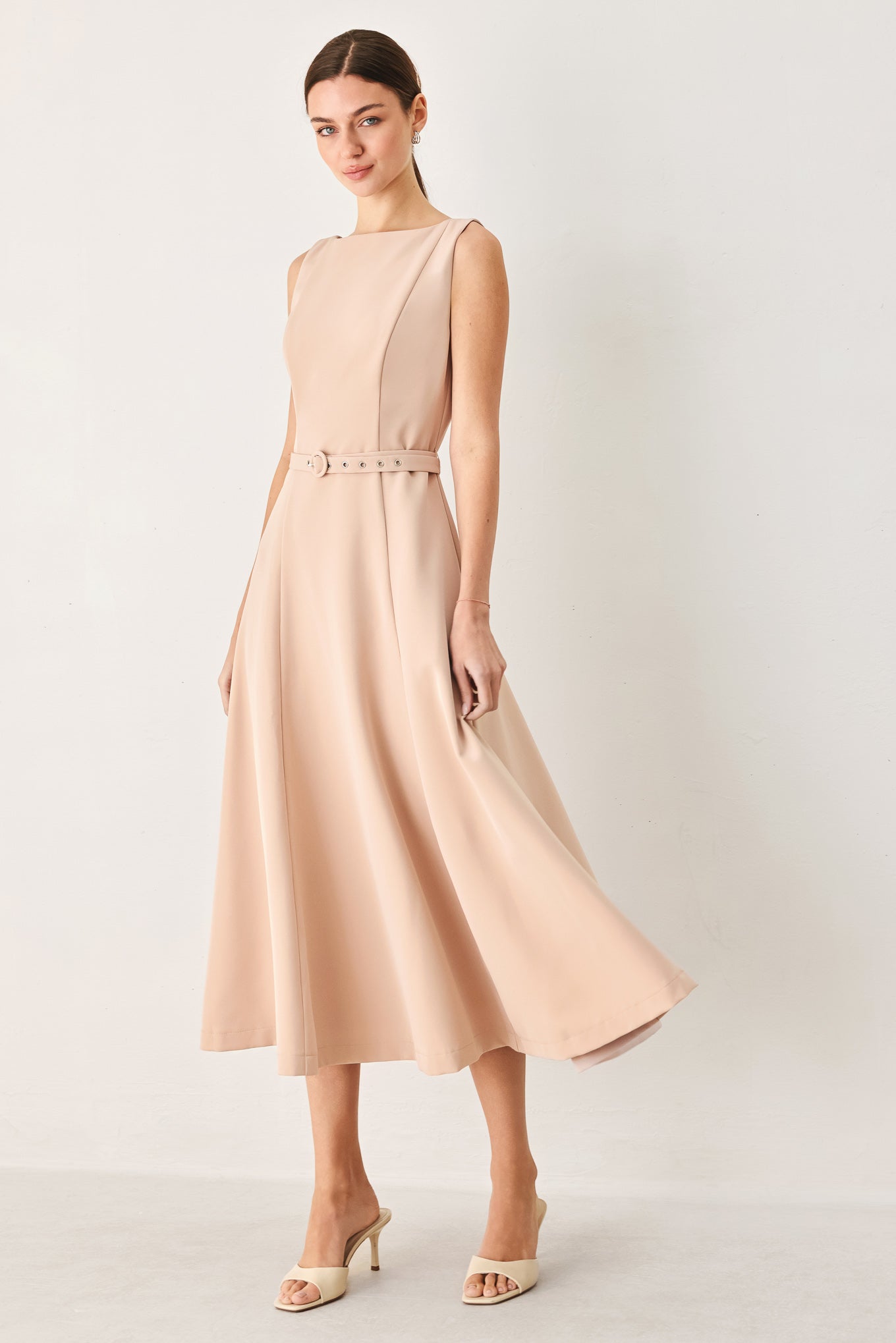 Woman wearing a sleeveless soft blush midi dress featuring boat neckline, circle skirt, self belt and back zipper closure | FREEMARKET