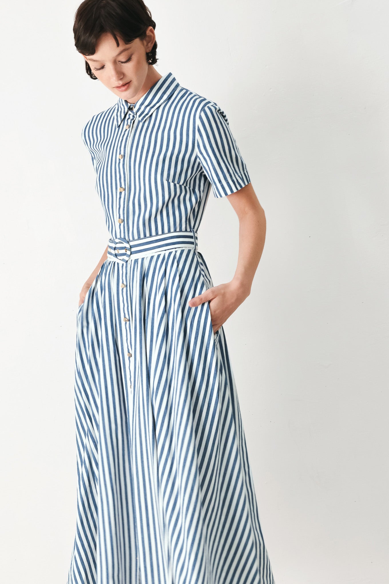 Woman wearing a denim blue and white striped midi shirt dress with self belt and full skirt | FREEMARKET