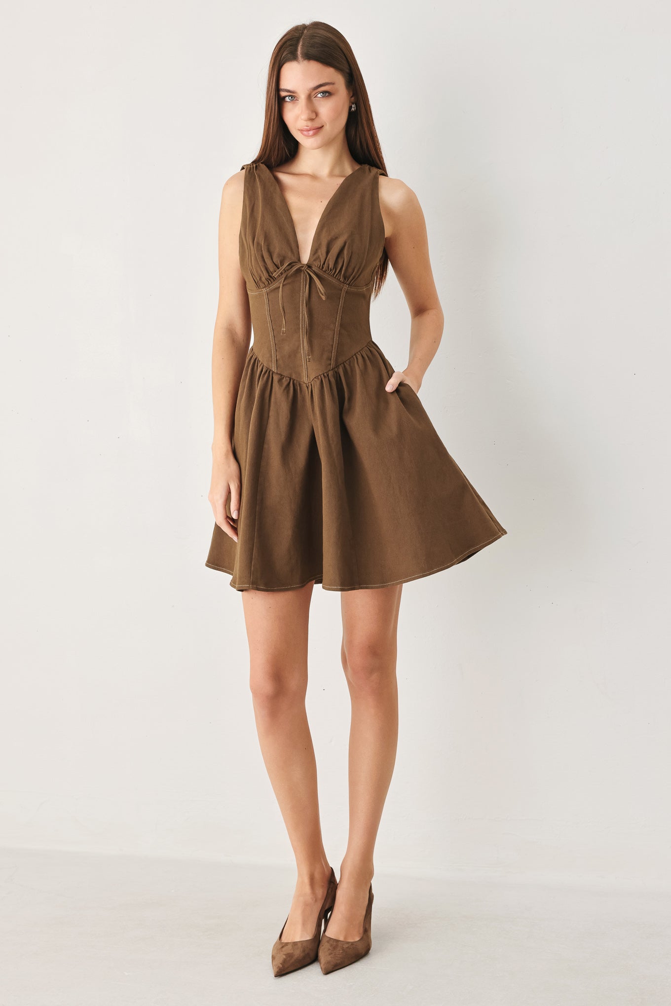 Woman wearing a washed brown woven mini dress featuring V neckline with tie, sleeveless, corset waist, full skirt and back zipper closure | FREEMARKET