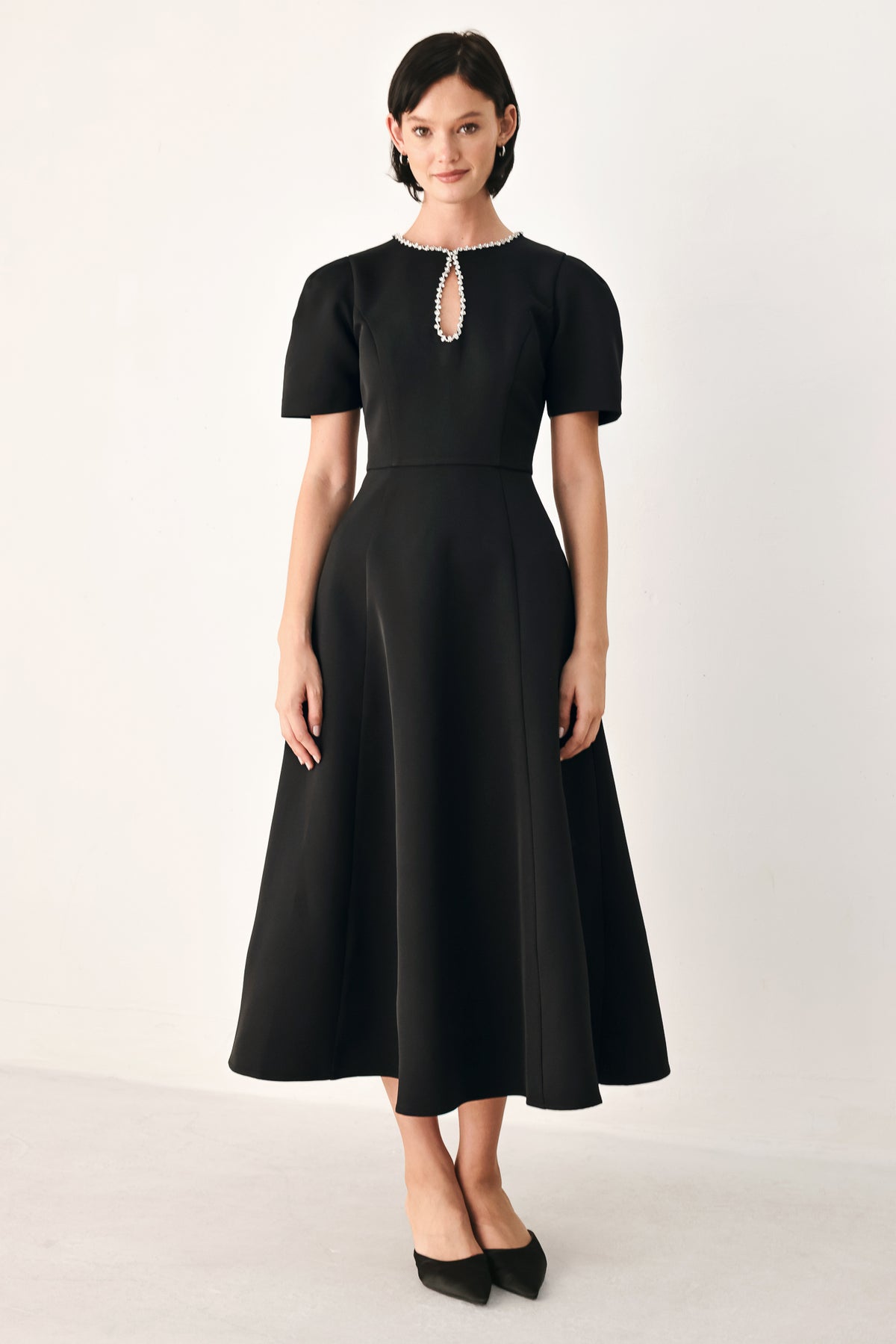 A woman modeling a black midi dress with short puff sleeves, a keyhole neckline with rhinestone embellishments, and a flared skirt | FREEMARKET