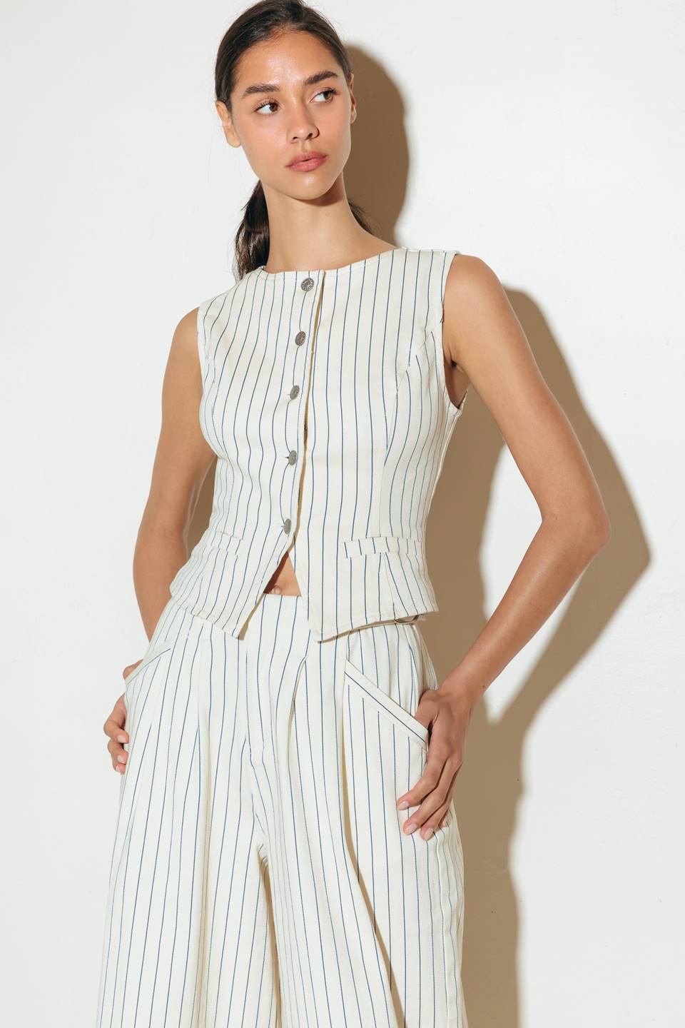 A striped woven vest featuring round neckline, sleeveless and front button closure