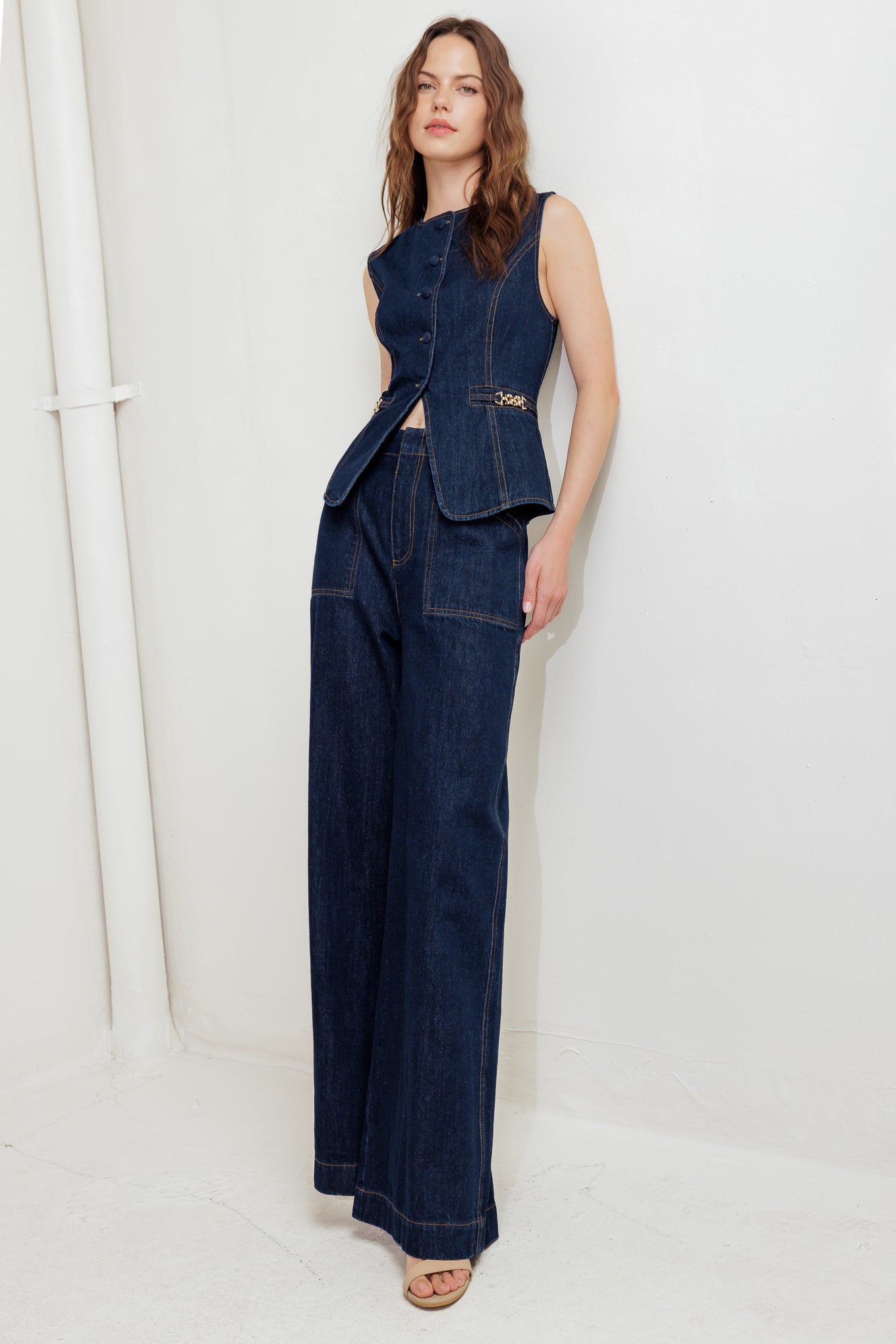 A denim vest featuring round neckline, sleeveless, front button down and hardware trim.