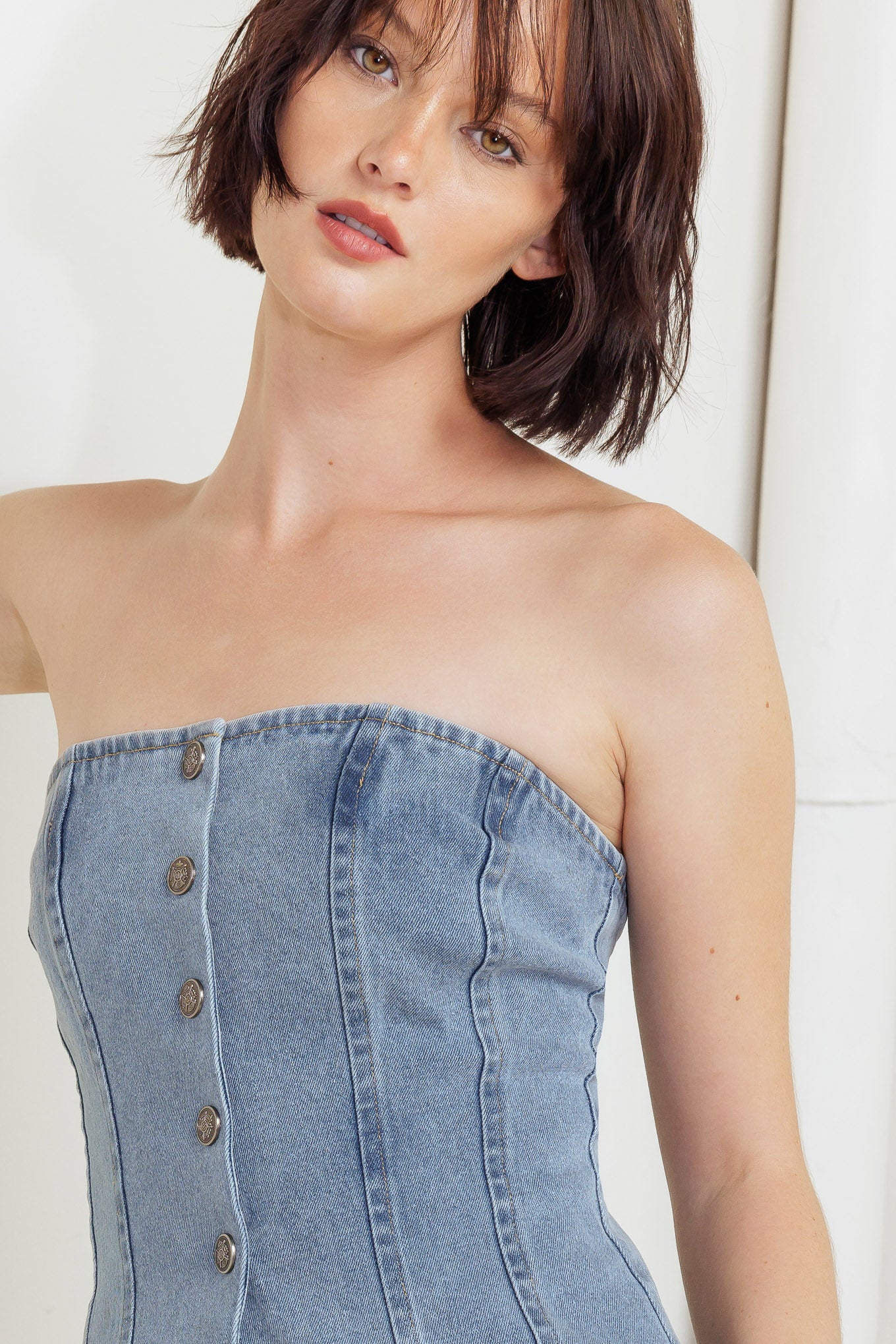 A strapless, washed denim top featuring a front button down