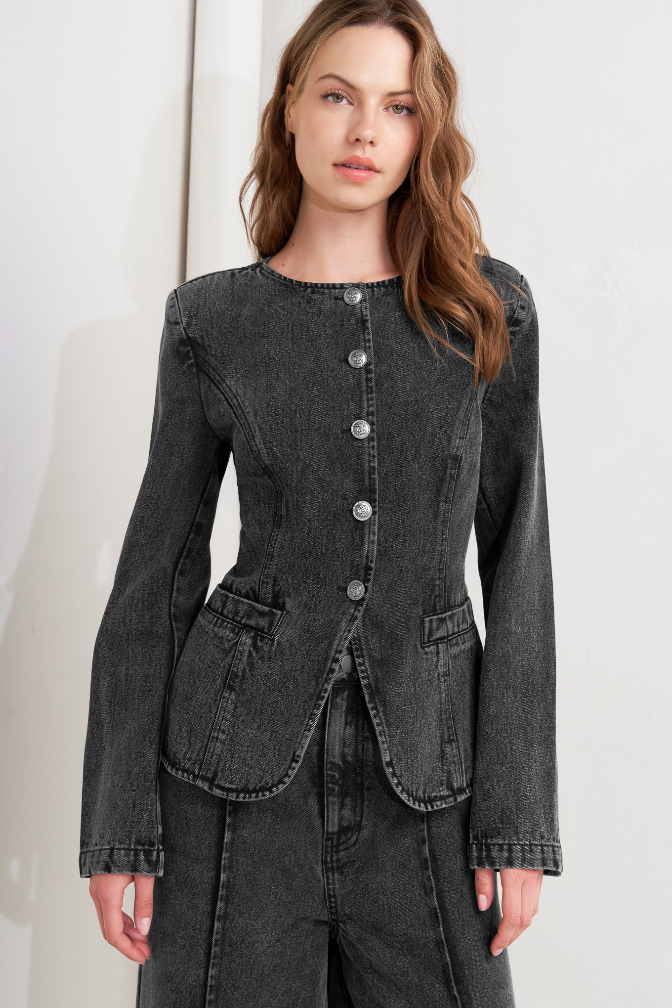 A washed denim jacket featuring round neckline and front button closure with pockets.